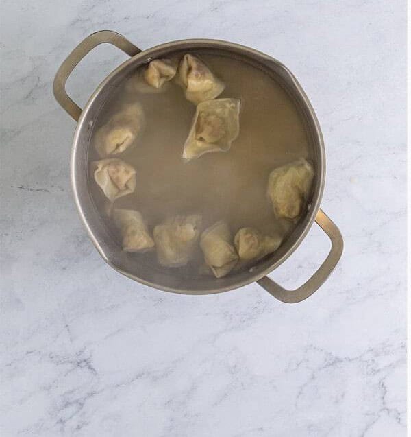 Pork filled wontons boiling gently in a pot of water until cooked through.