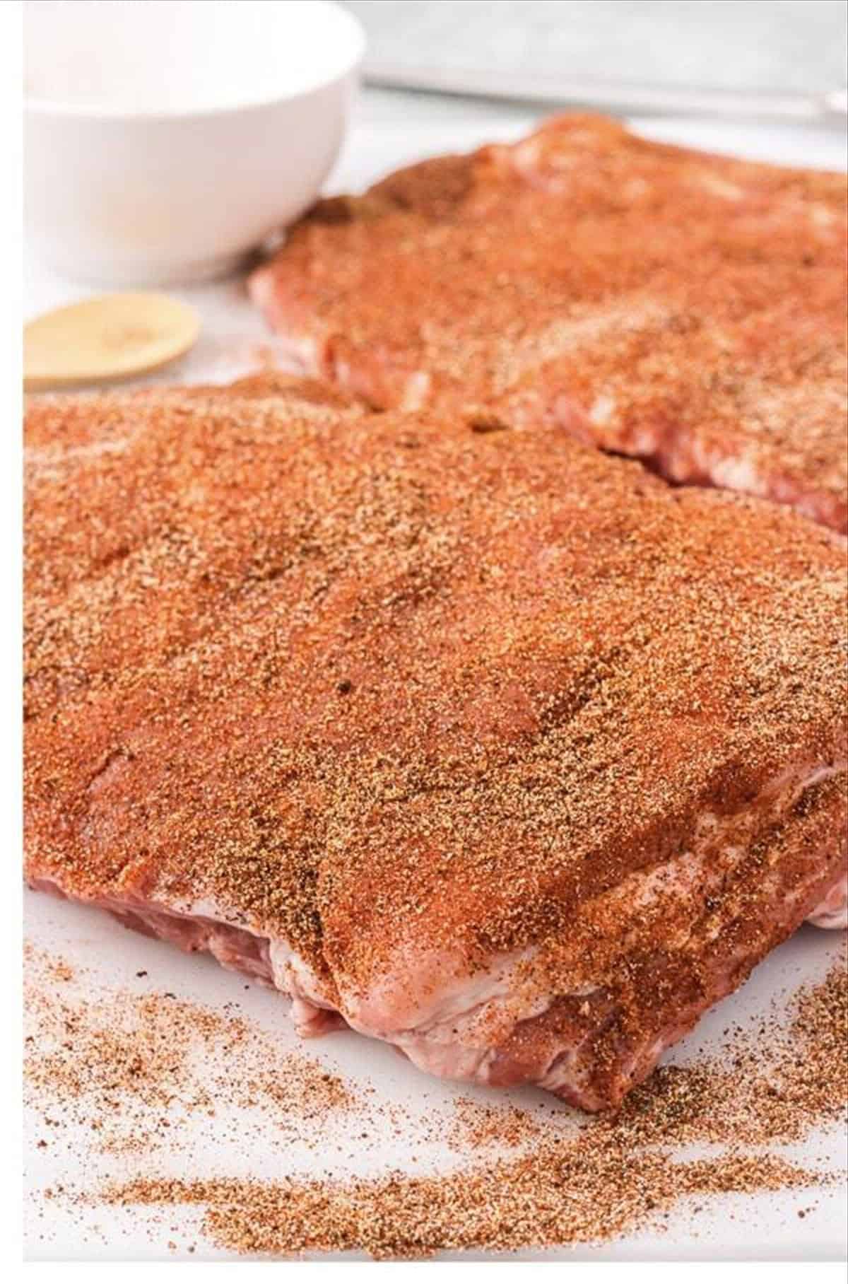 Spice rub applied to St. Louis ribs on a baking sheet.