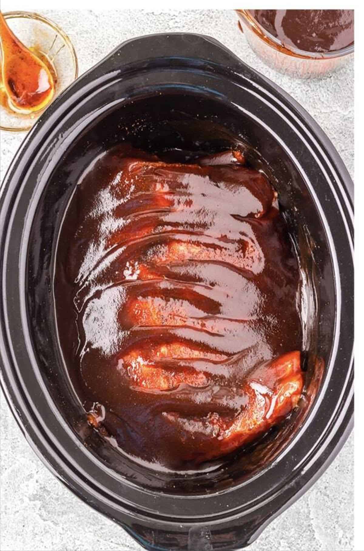 Honey chipotle bbq sauce poured over ribs in a slow cooker.