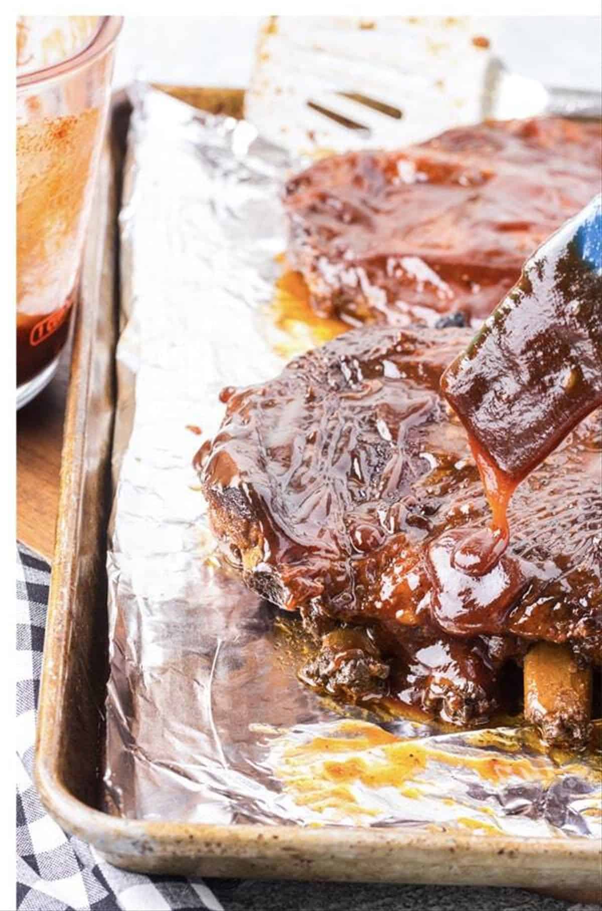 Broiled St. Louis ribs caramelized on a foil-lined sheet pan.