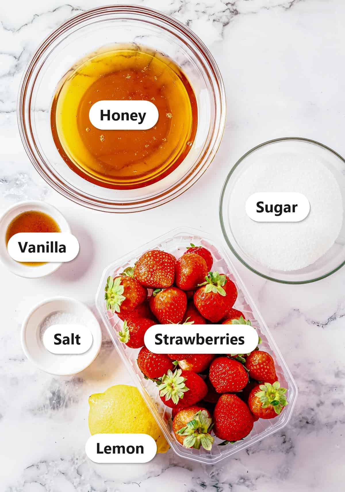 Labeled ingredients for honey strawberry butter including honey, vanilla, sugar, salt, fresh strawberries, and lemon.