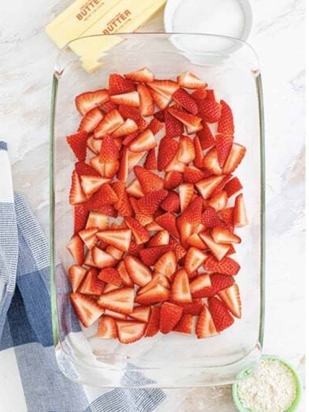 Fresh quartered strawberries spread in a baking dish for Strawberry Dump Cake.