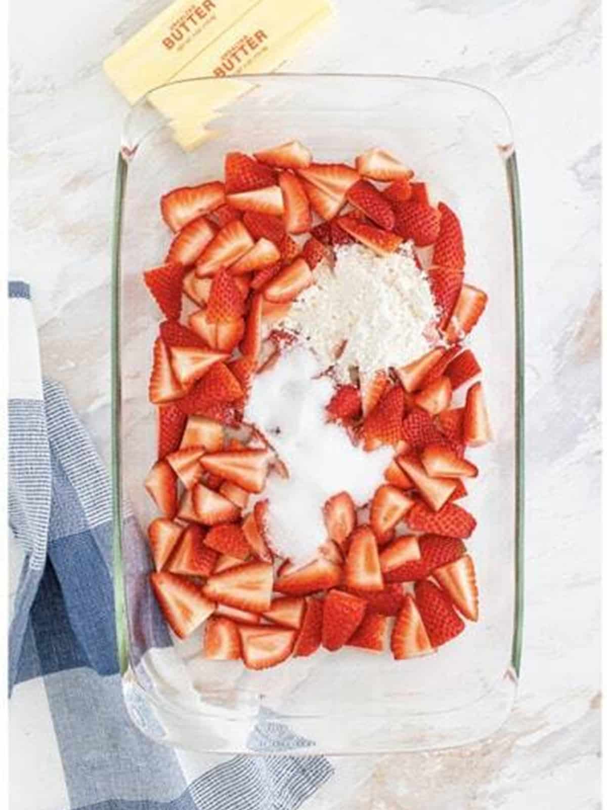 Sugar and flour sprinkled over the fresh strawberries in the baking dish.