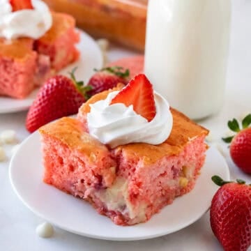 Slice of Strawberry Earthquake Cake on a plate with cheesecake swirl visible and fresh strawberries on top.