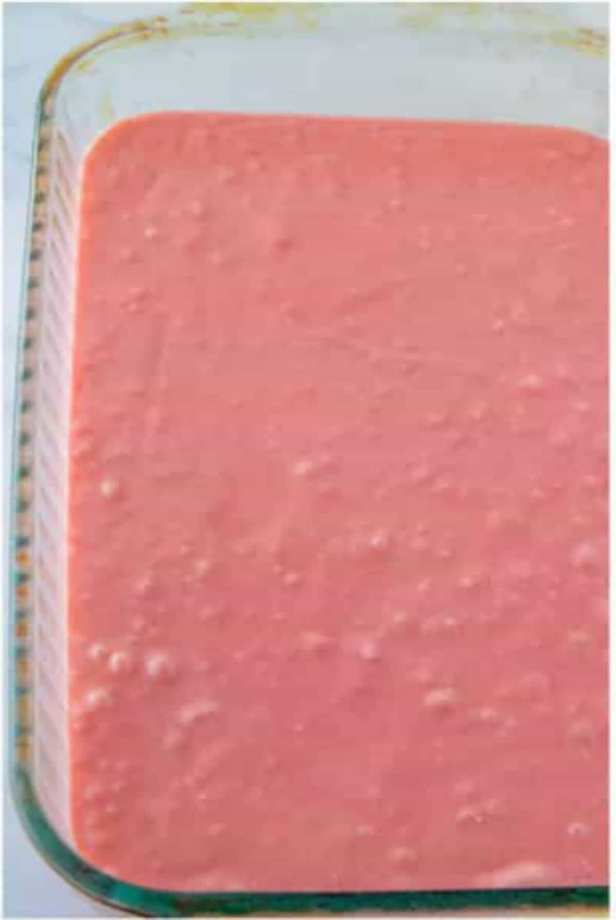 Strawberry cake batter spread in a glass baking dish.