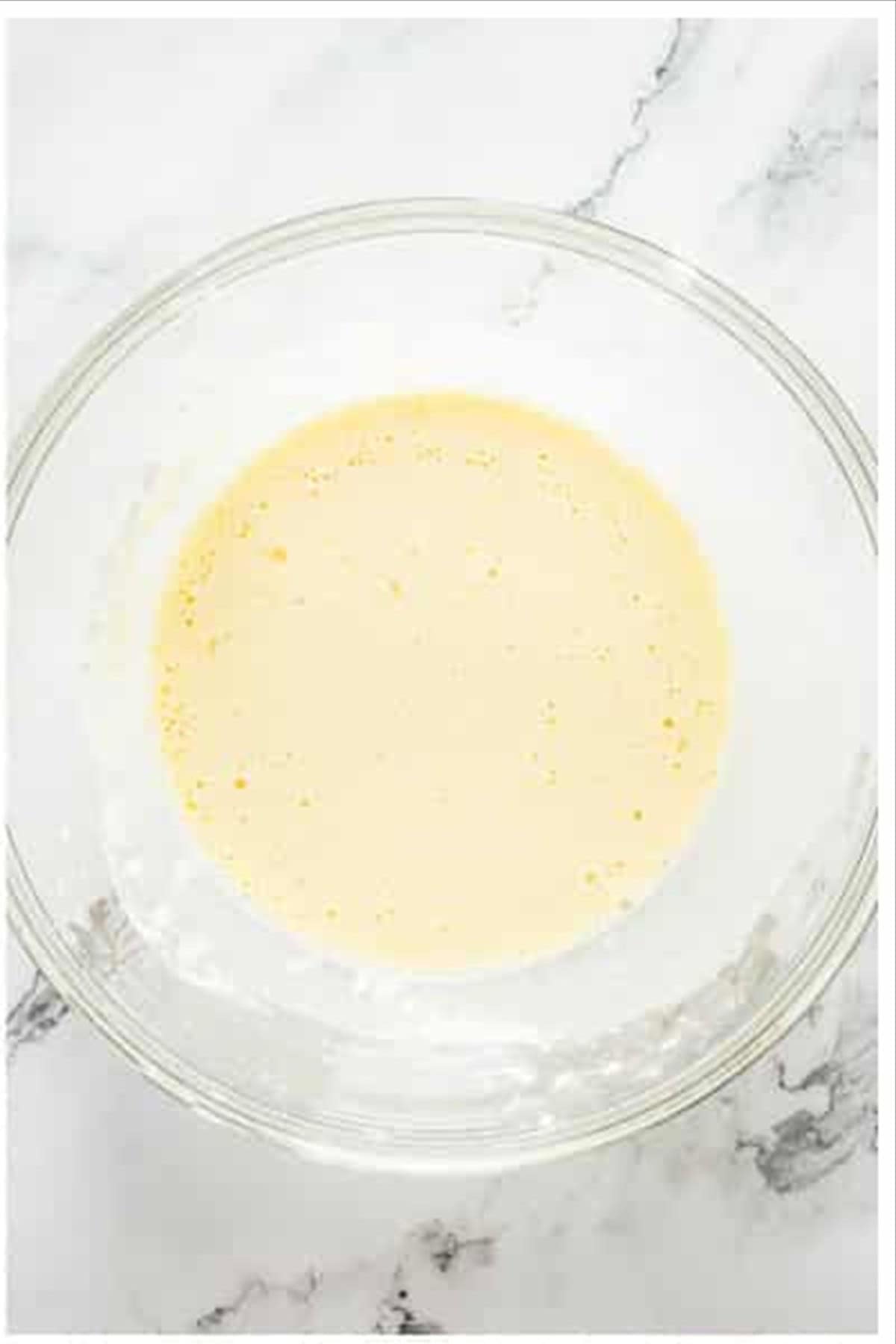 Egg and ice water whisked together in a glass bowl for the batter.