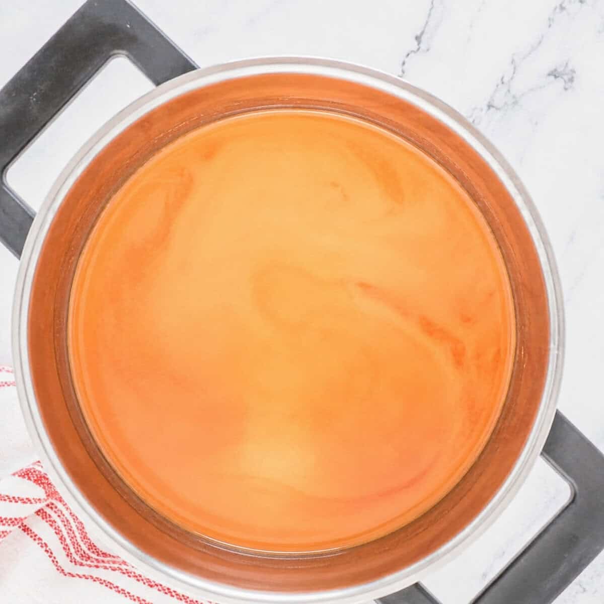 Sweet and Sour Sauce with ketchup just whisked in turning orange in the saucepan.