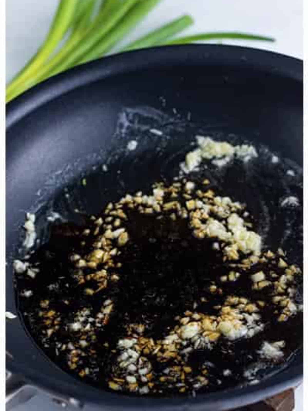 Adding minced garlic to the melted butter in the skillet.