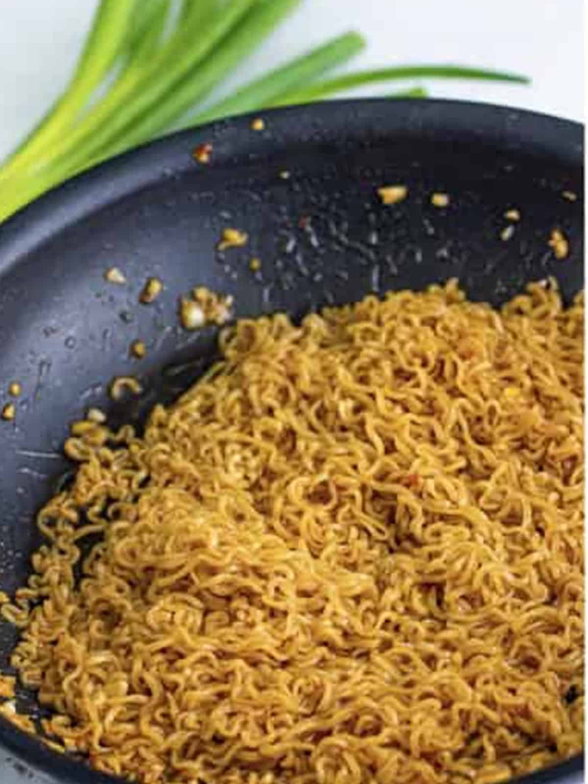 Tossing the ramen noodles to coat them in the glaze.