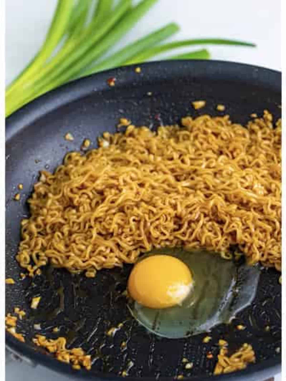 Cracking an egg into the skillet with the TikTok ramen noodles.