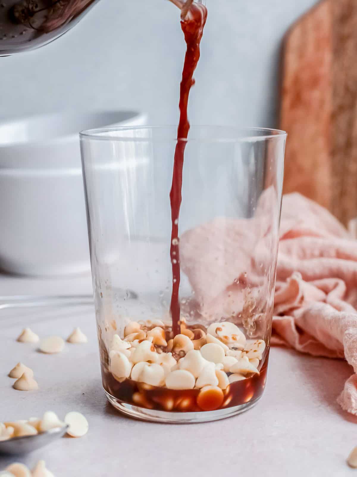 Pouring hot espresso over white chocolate chips in a glass for a white chocolate mocha frappuccino.