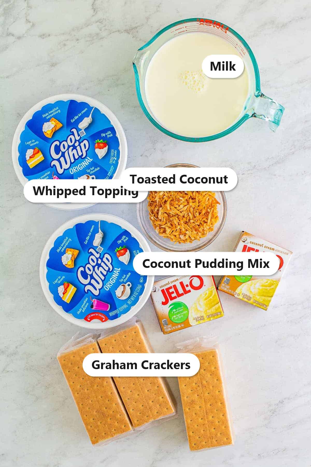 Ingredients to make a Coconut Icebox Cake labeled including coconut pudding mix, milk, whipped topping, graham crackers, and toasted coconut.