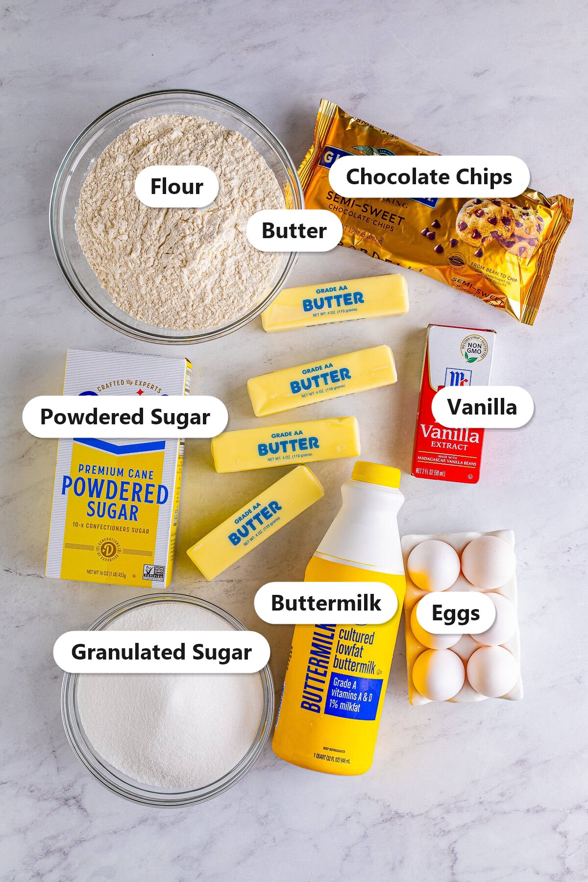 Labeled ingredients for chocolate chip pound cake including flour, sugar, powdered sugar, butter, eggs, buttermilk, vanilla, and chocolate chips.