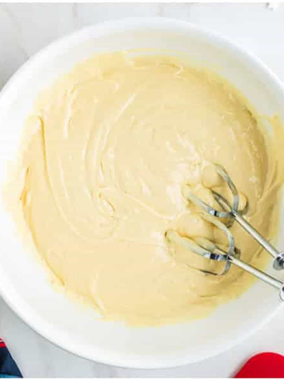 Vanilla cake batter mixed in a white bowl for a 4th of July Cake.