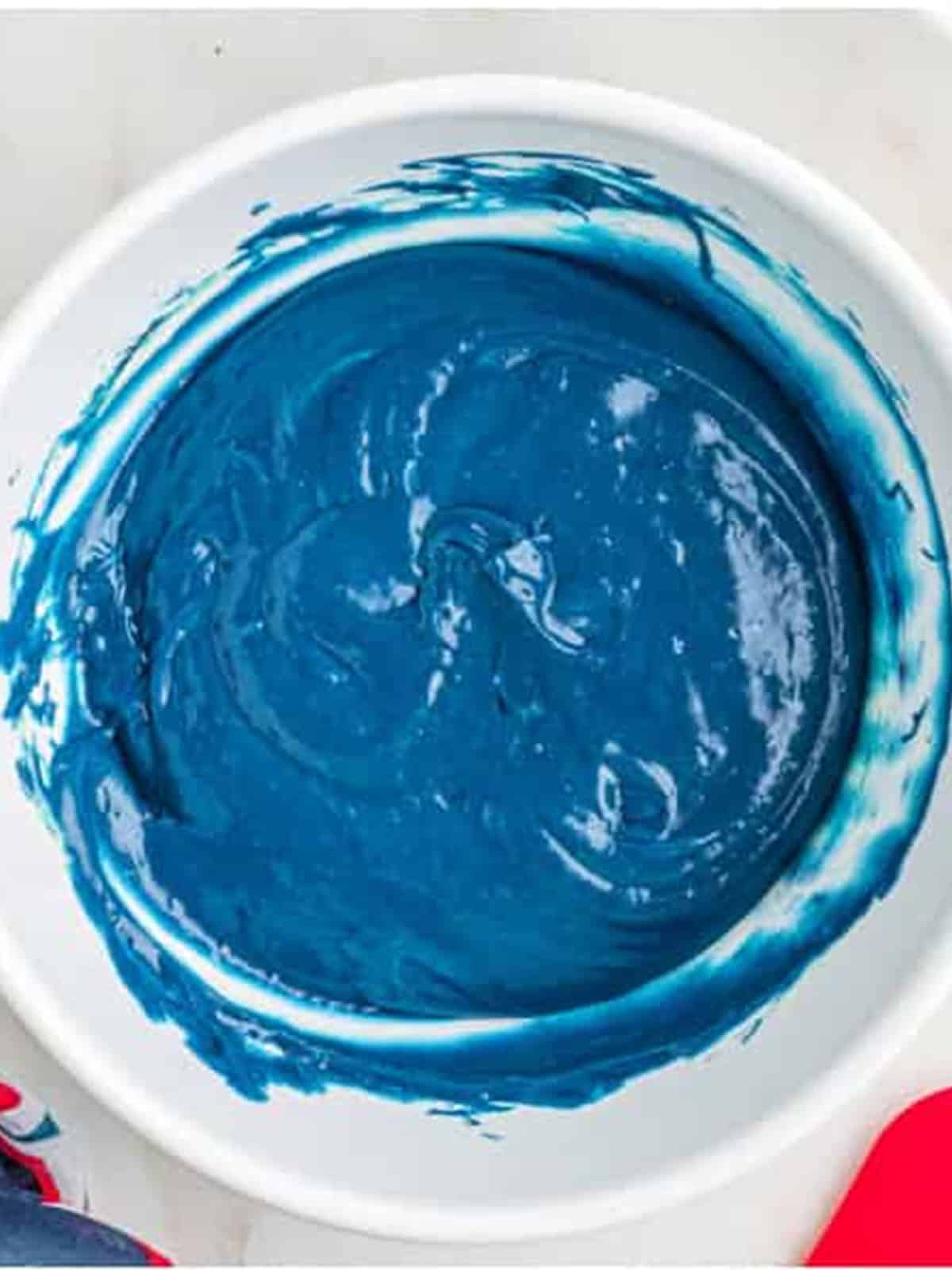 Blue tinted cake batter in a white bowl for a 4th of July Cake.