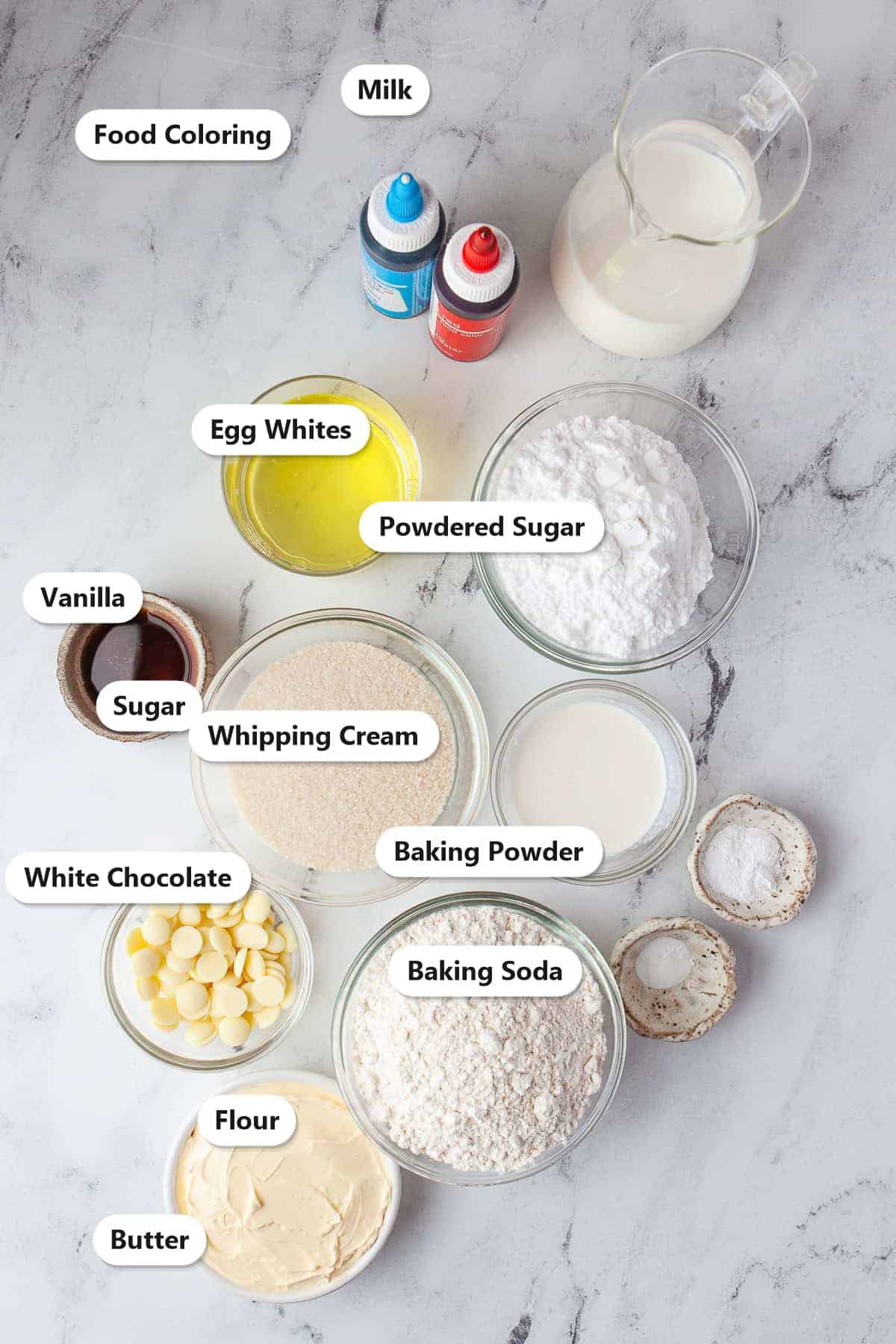 Labeled ingredients for 4th of July cupcakes including flour, butter, sugar, powdered sugar, white chocolate, egg whites, milk, whipping cream, baking powder, baking soda, vanilla, and food coloring.