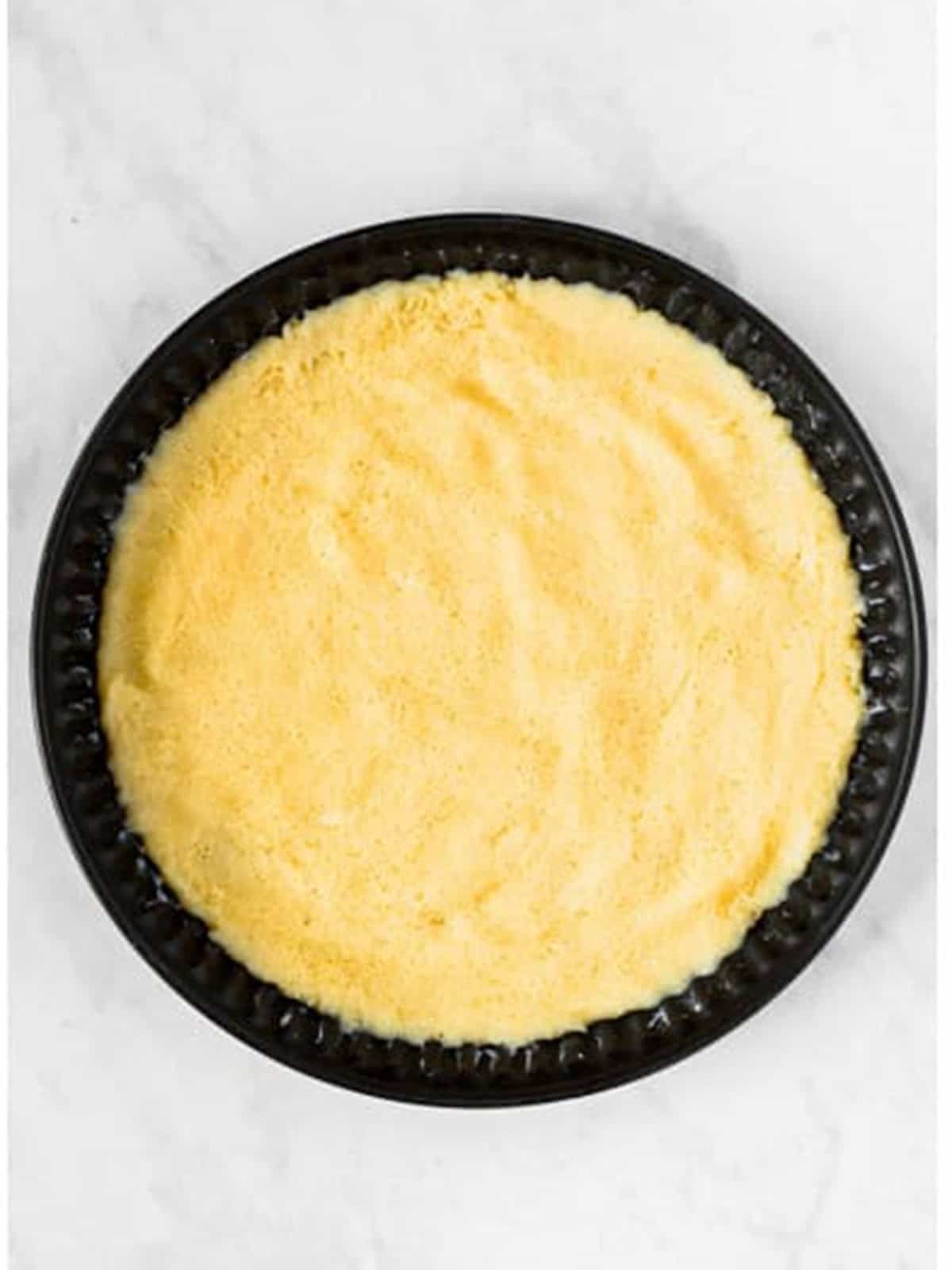 Golden baked sugar cookie crust in a round pan for 4th of july fruit pizza.