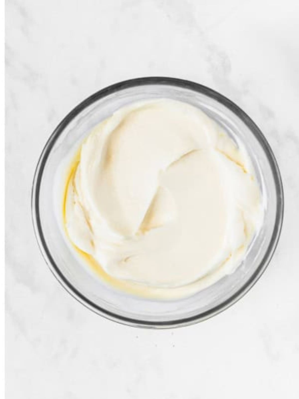 Cream cheese frosting whipped smooth in a glass bowl for 4th of july fruit pizza.