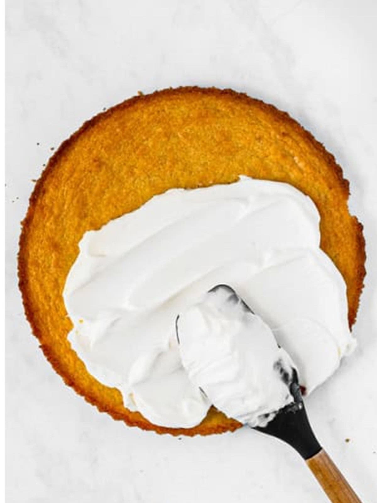 Cream cheese frosting spread over the cooled sugar cookie crust with a spatula.