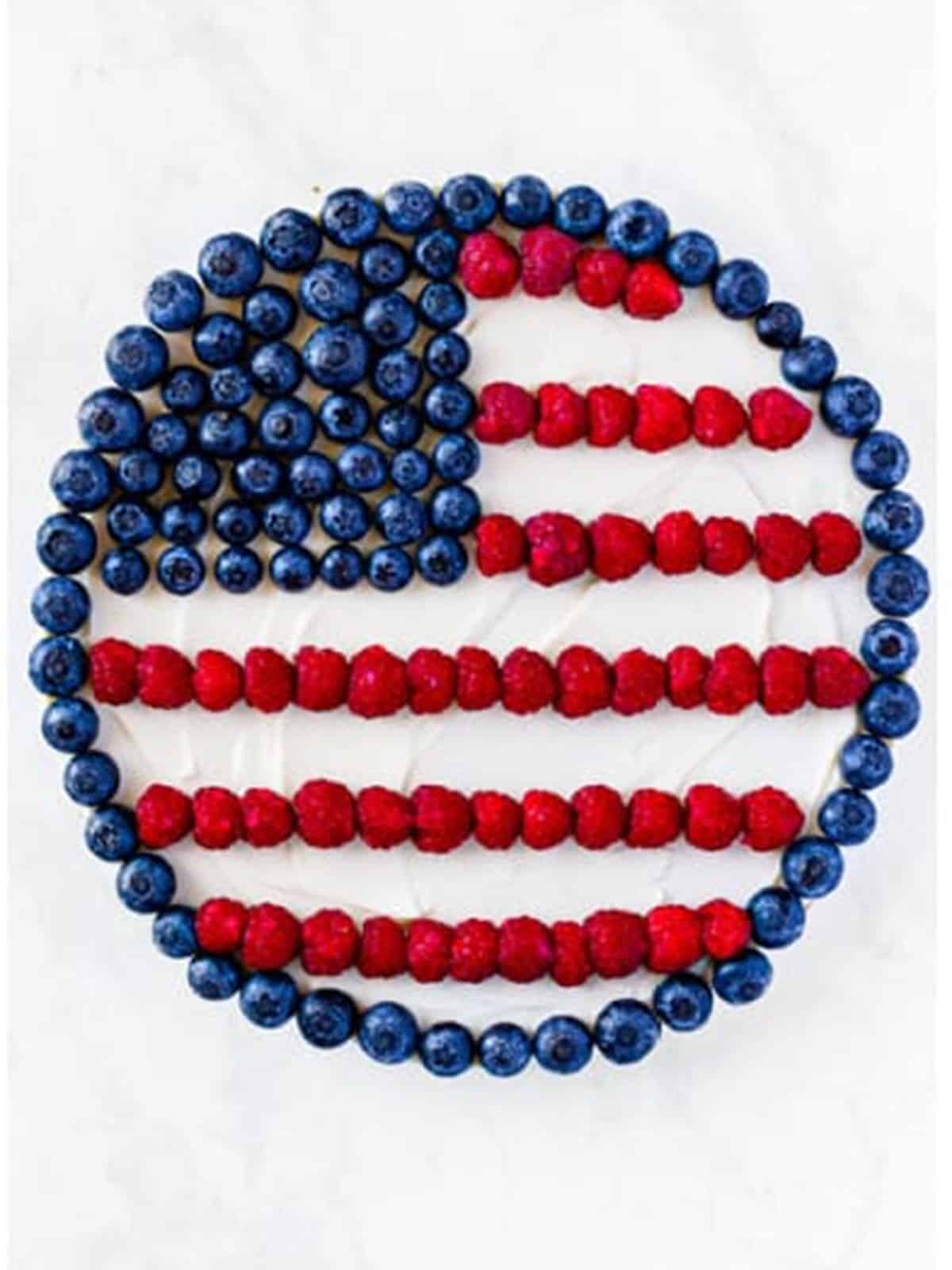 Blueberries and raspberries arranged as an American flag with piped frosting stripes on the fruit pizza.