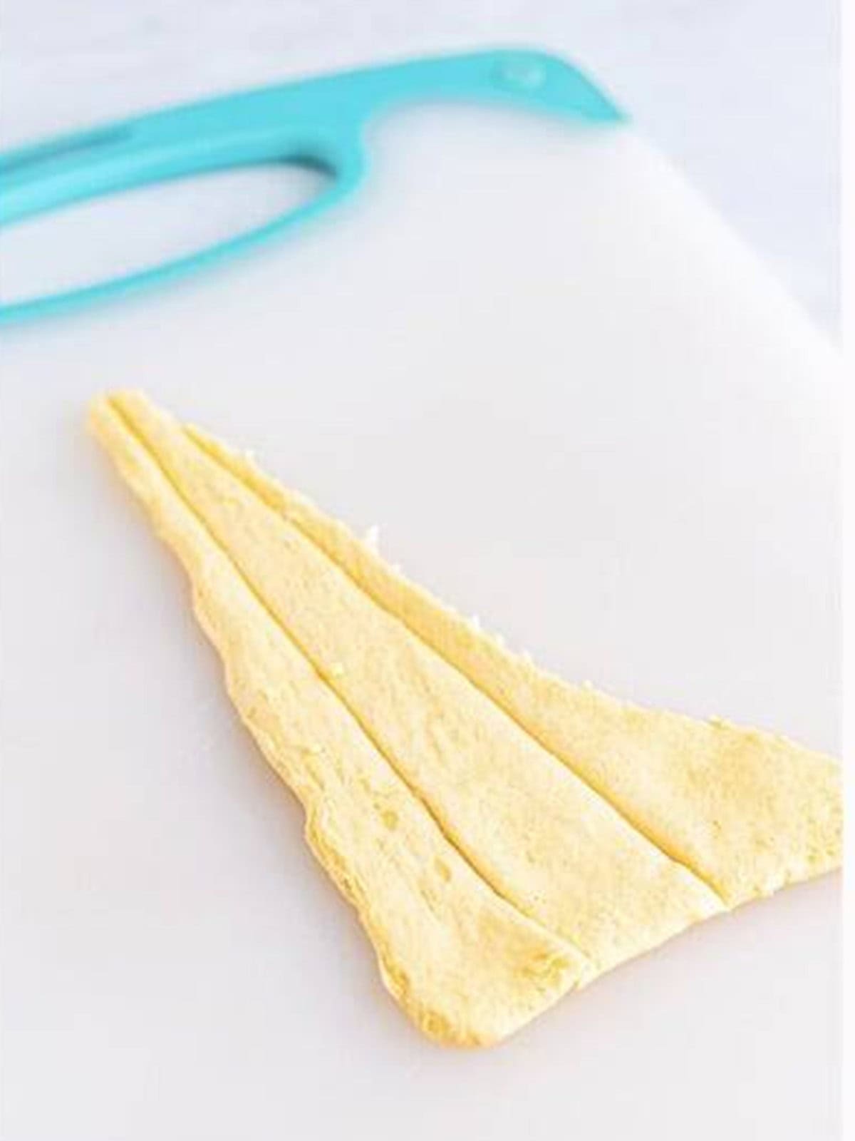 Crescent roll dough cut into thin triangles on a cutting board.