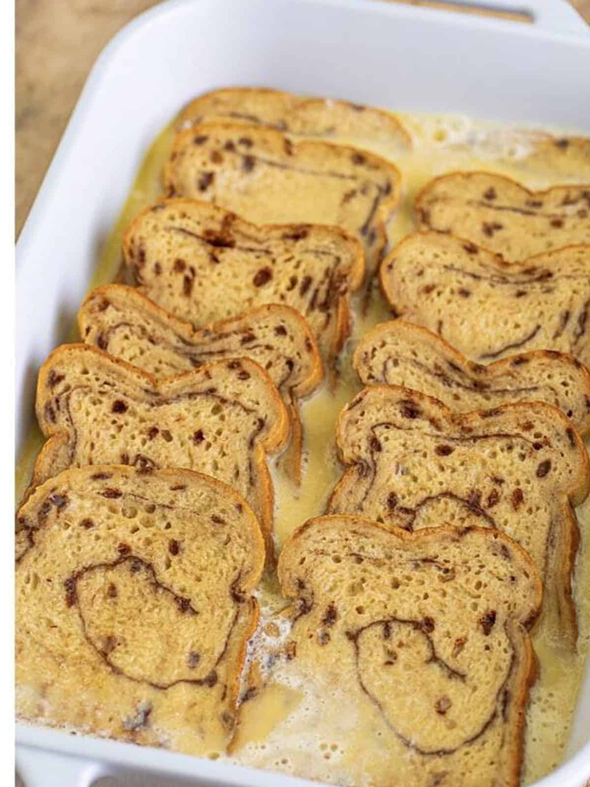 Egg custard poured over cinnamon swirl bread in a baking dish.