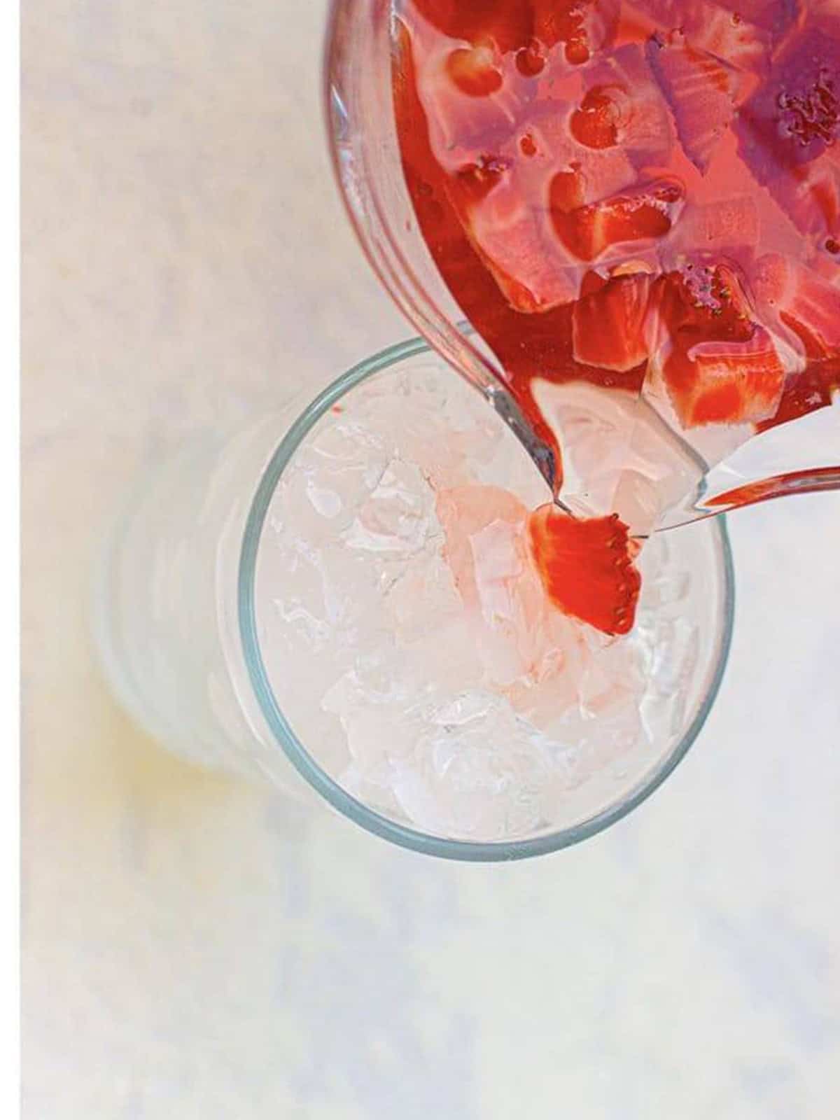 Strawberry Acai Refresher poured over crushed ice in a glass.