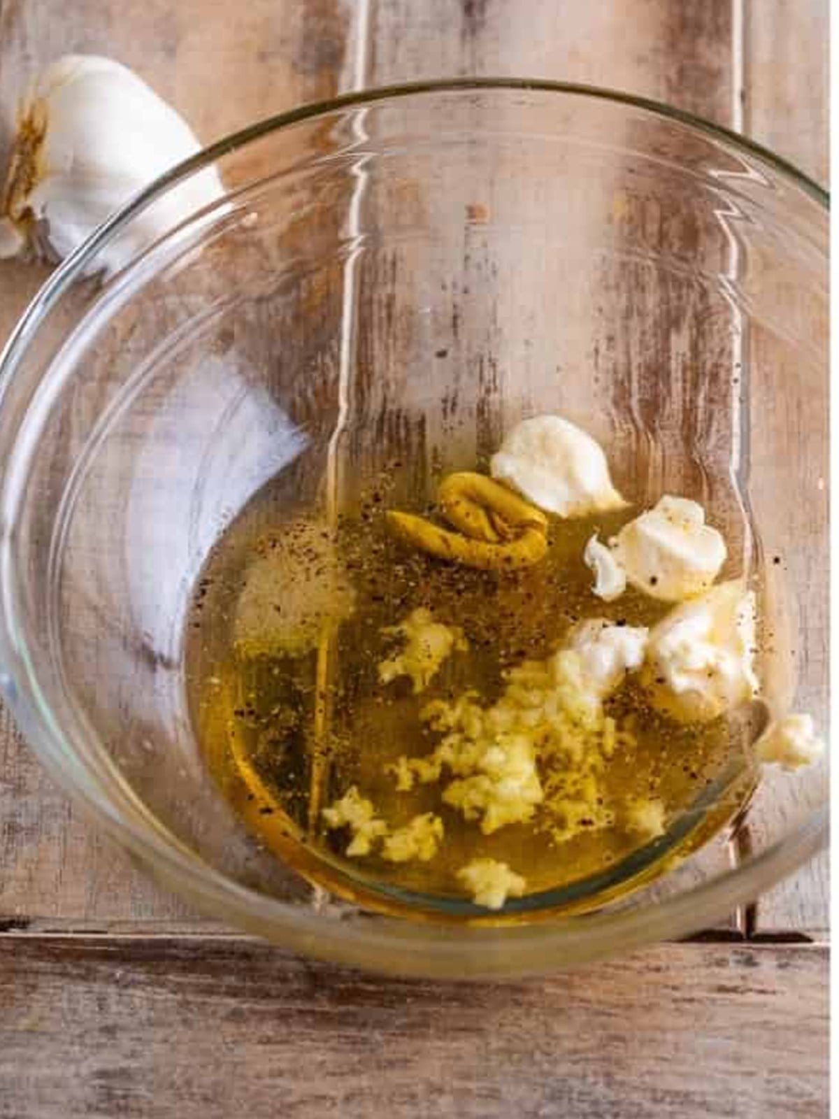 Whisking apple cider vinegar, honey, garlic, and dijon mustard in a bowl.