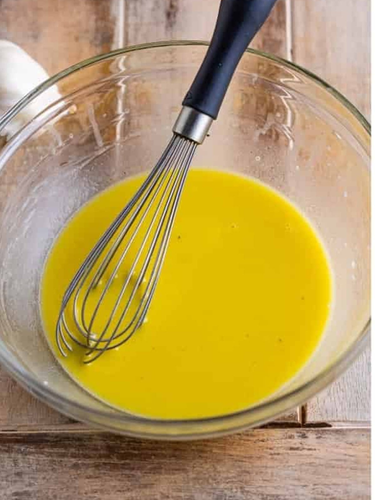 Streaming olive oil into the apple cider vinegar dressing while whisking.
