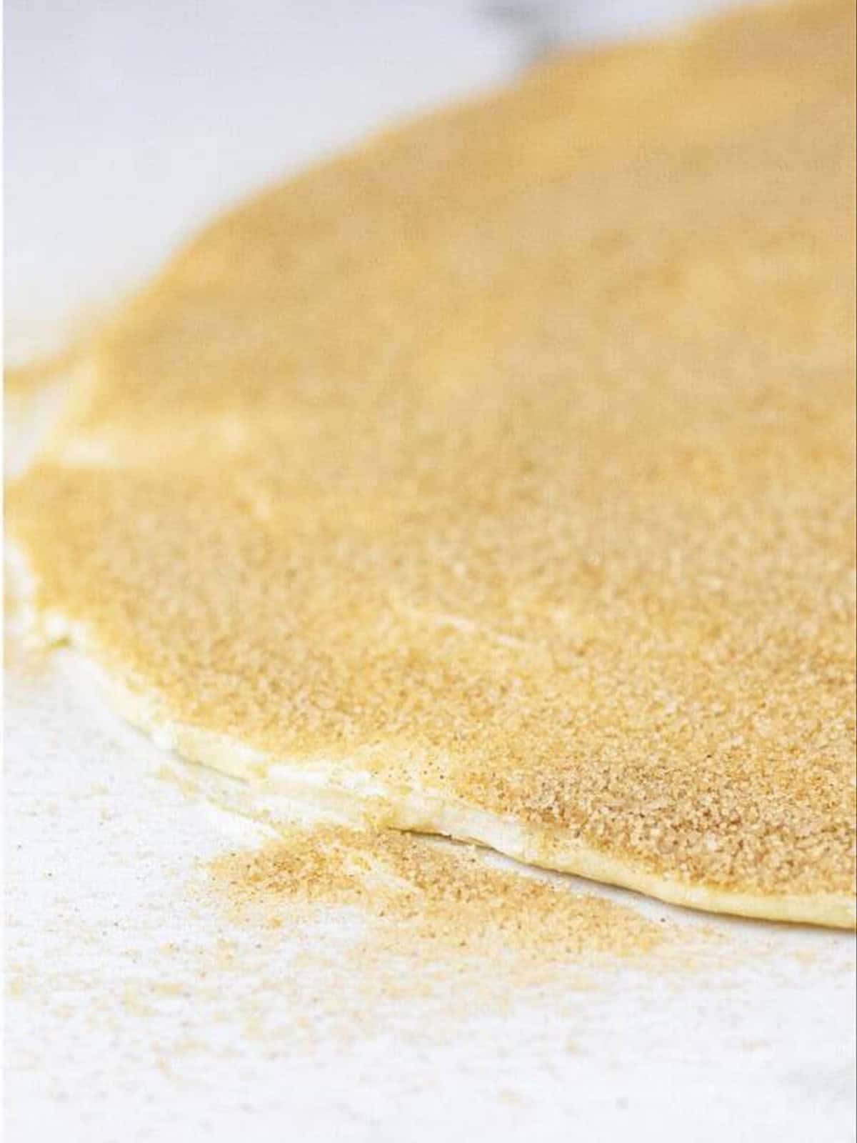Cinnamon roll dough rolled out thin and spread with cinnamon sugar filling.
