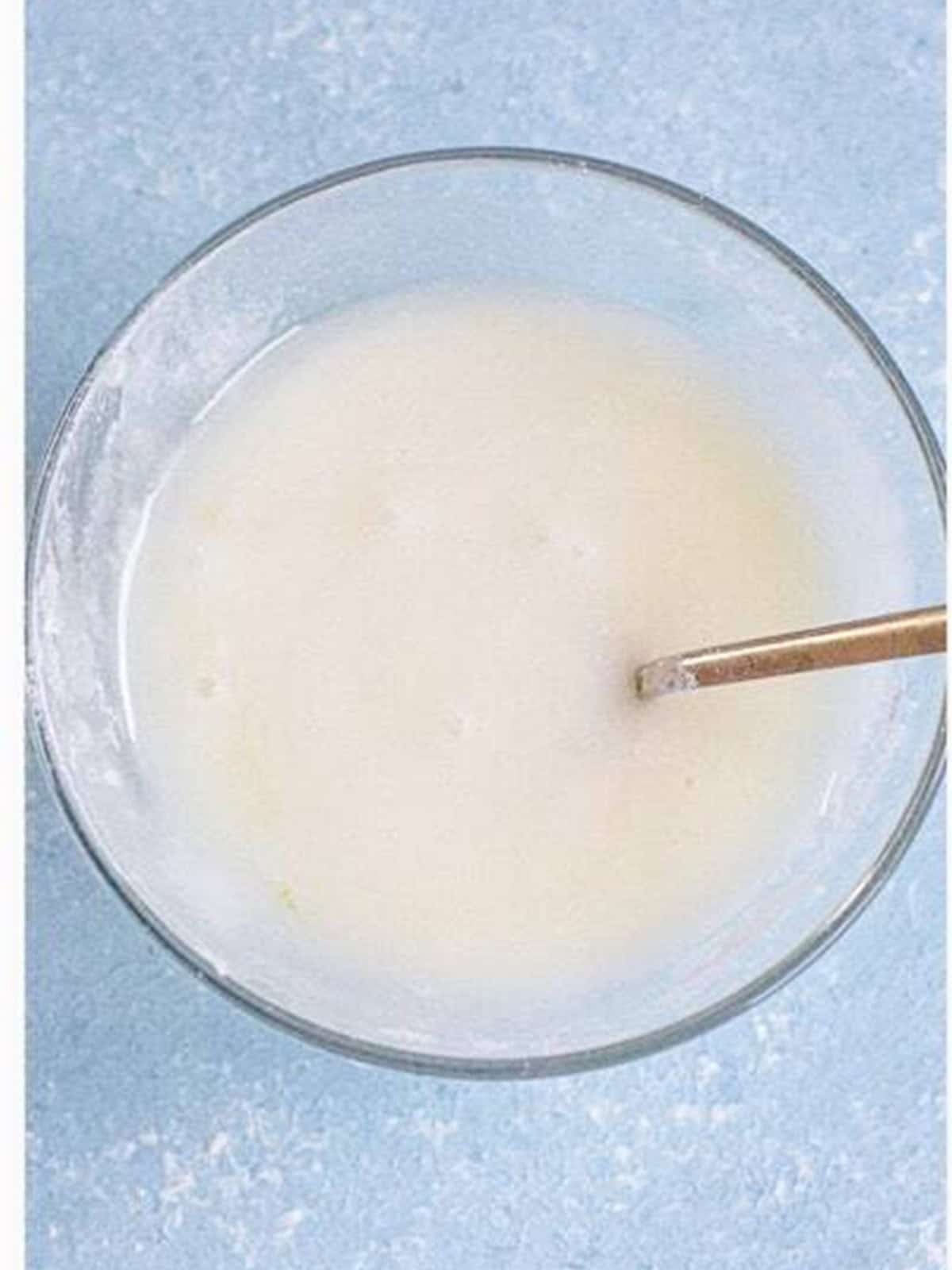 Heavy cream in a small bowl ready to brush over the air fryer cinnamon rolls.