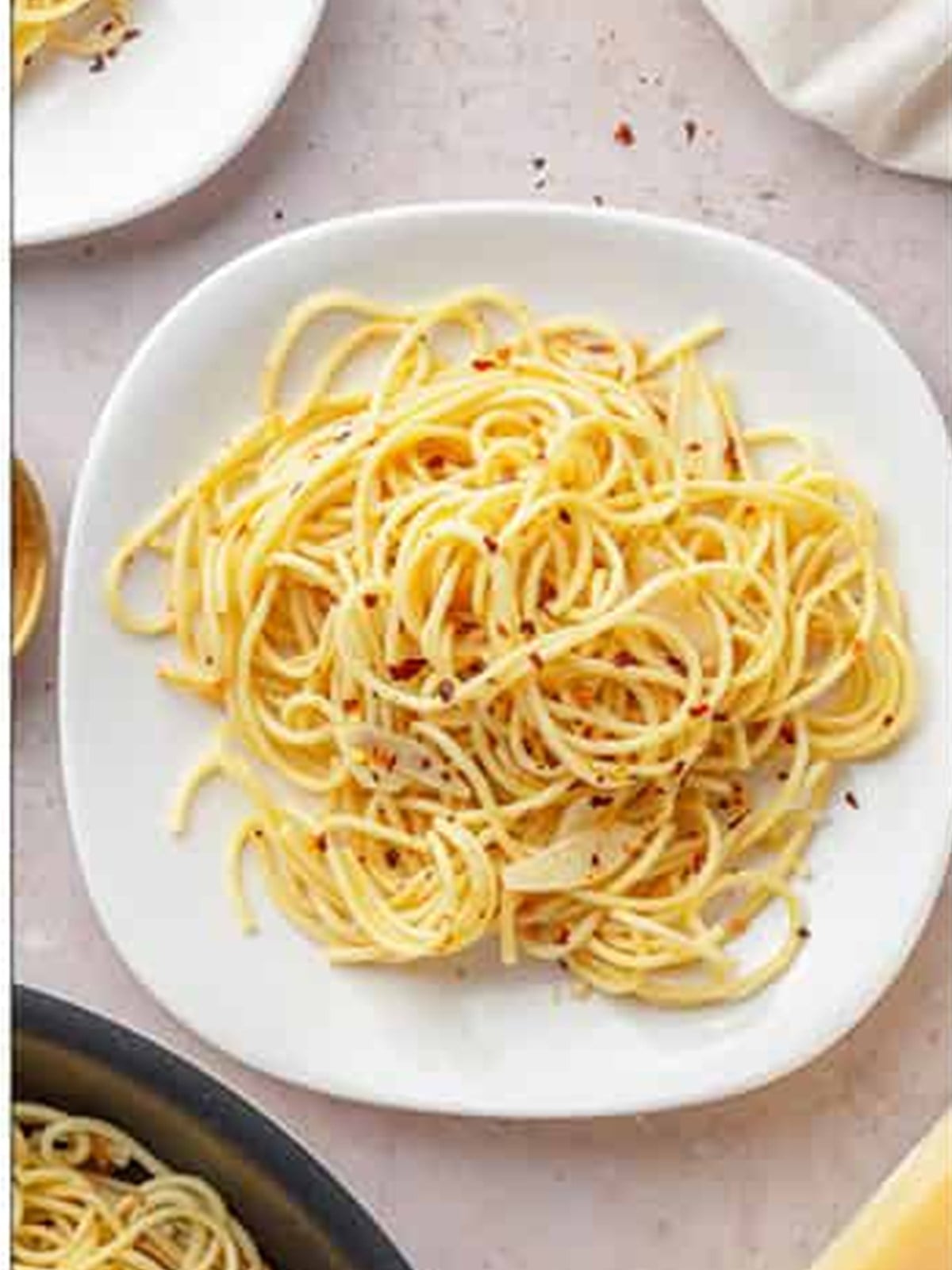 A plate of finished Aglio e Olio garnished with parsley and parmesan.