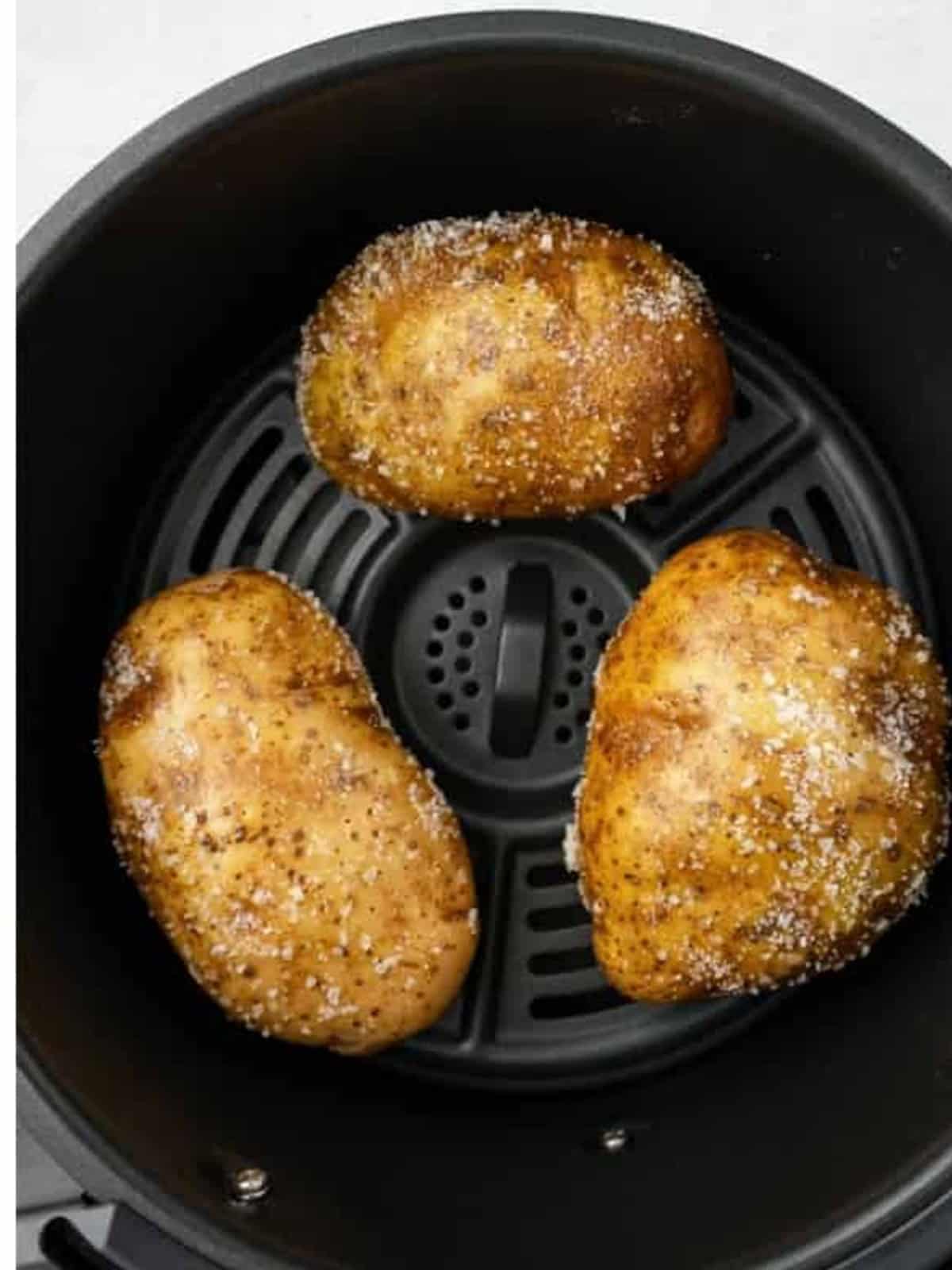 Seasoned russet potatoes arranged in an air fryer basket.