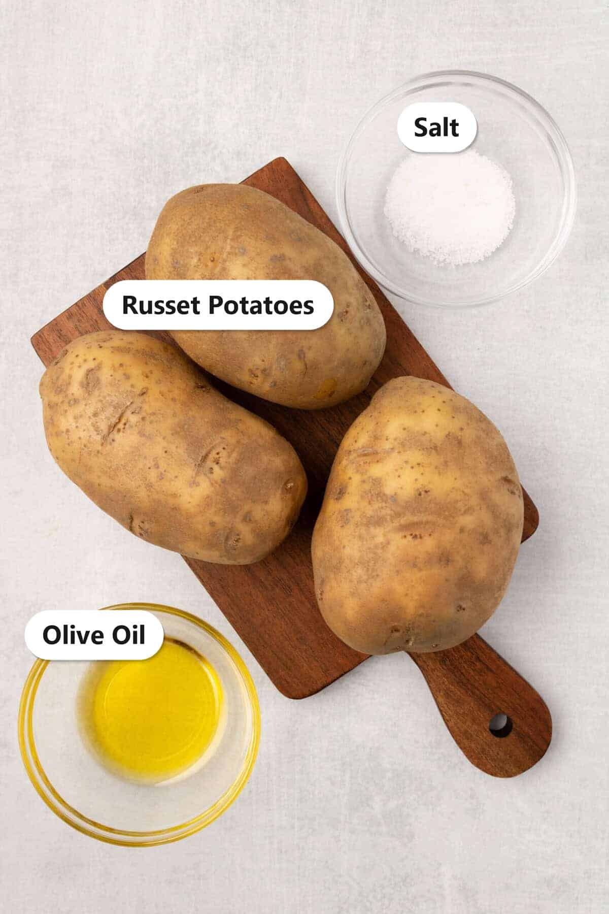Labeled ingredients for air fryer baked potatoes including russet potatoes, olive oil, and salt.