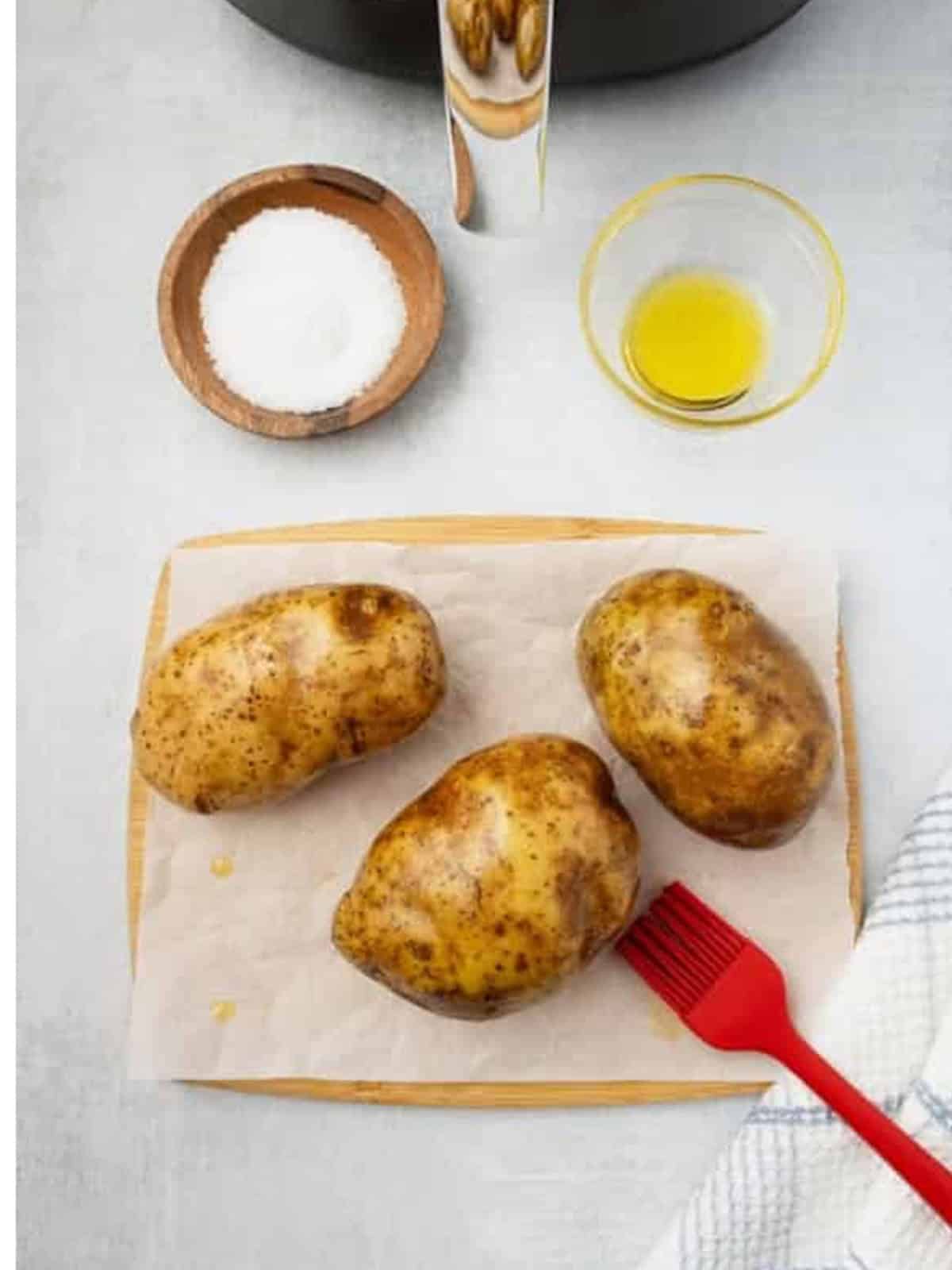 Russet potatoes pricked and brushed with olive oil on parchment.