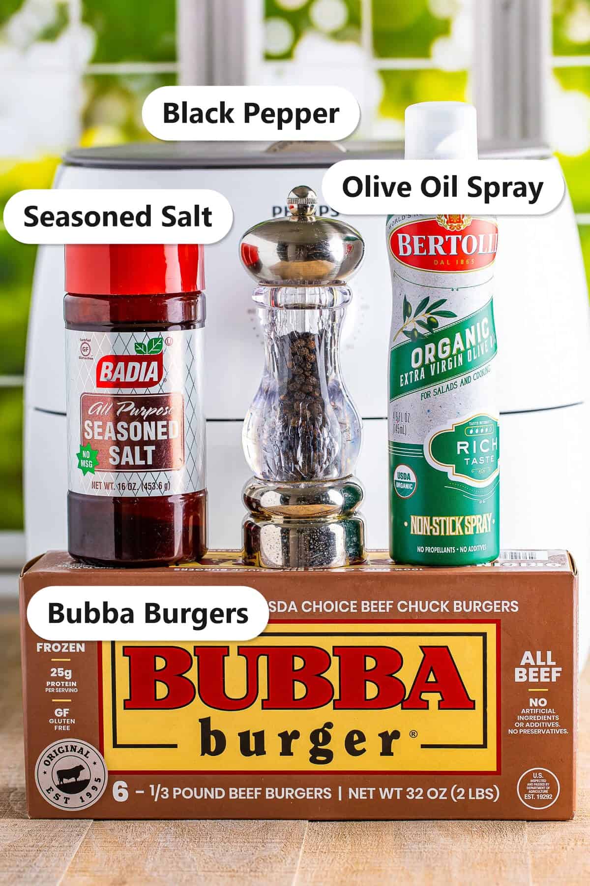 Labeled ingredients to make air fryer bubba burgers including frozen Bubba burgers, seasoned salt, black pepper, olive oil spray, and American cheese.