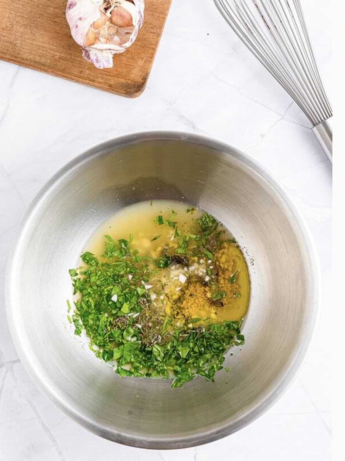 Lemon herb marinade whisked together in a metal bowl.