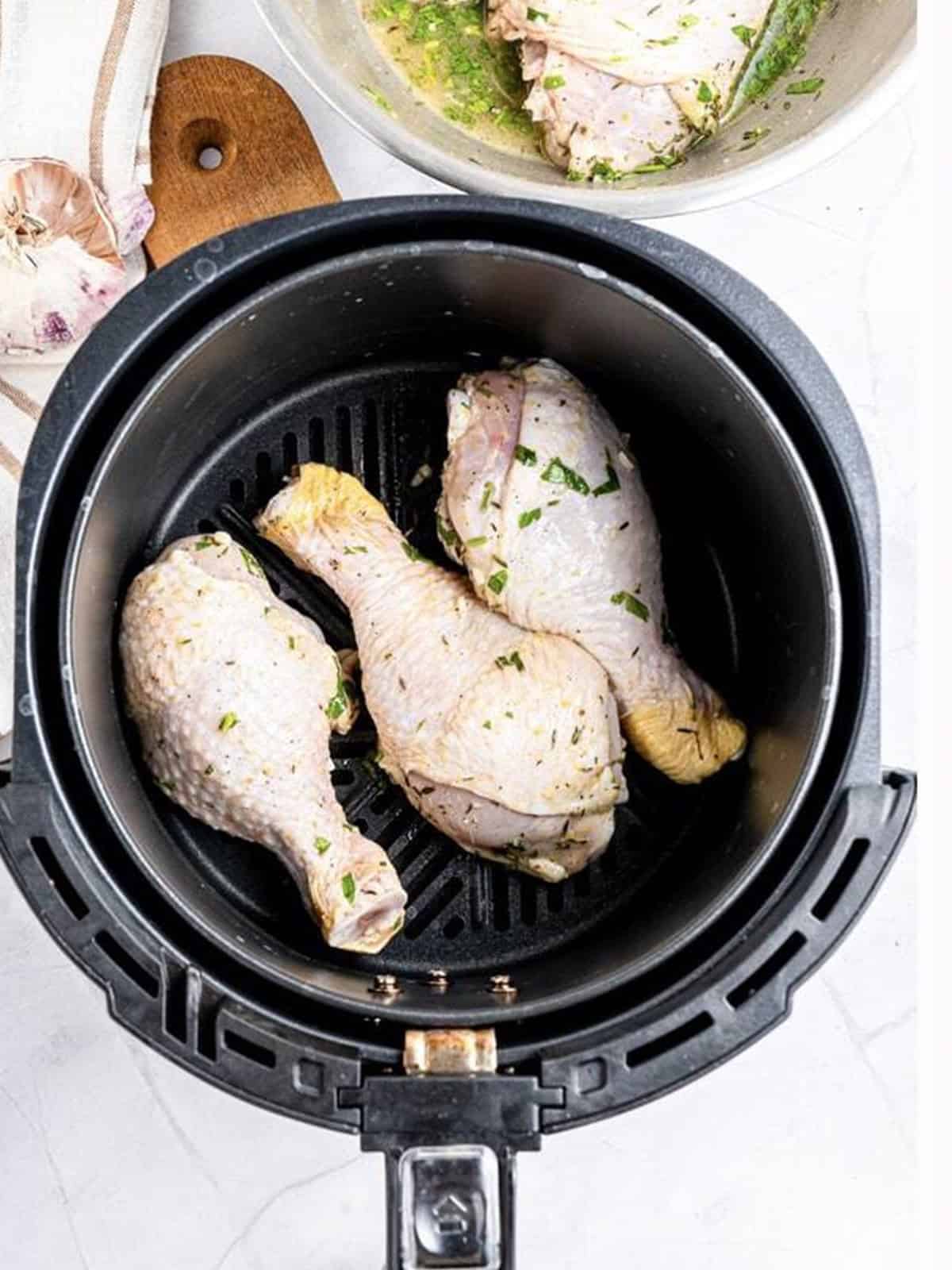Marinated chicken drumsticks arranged in a single layer in the air fryer basket.