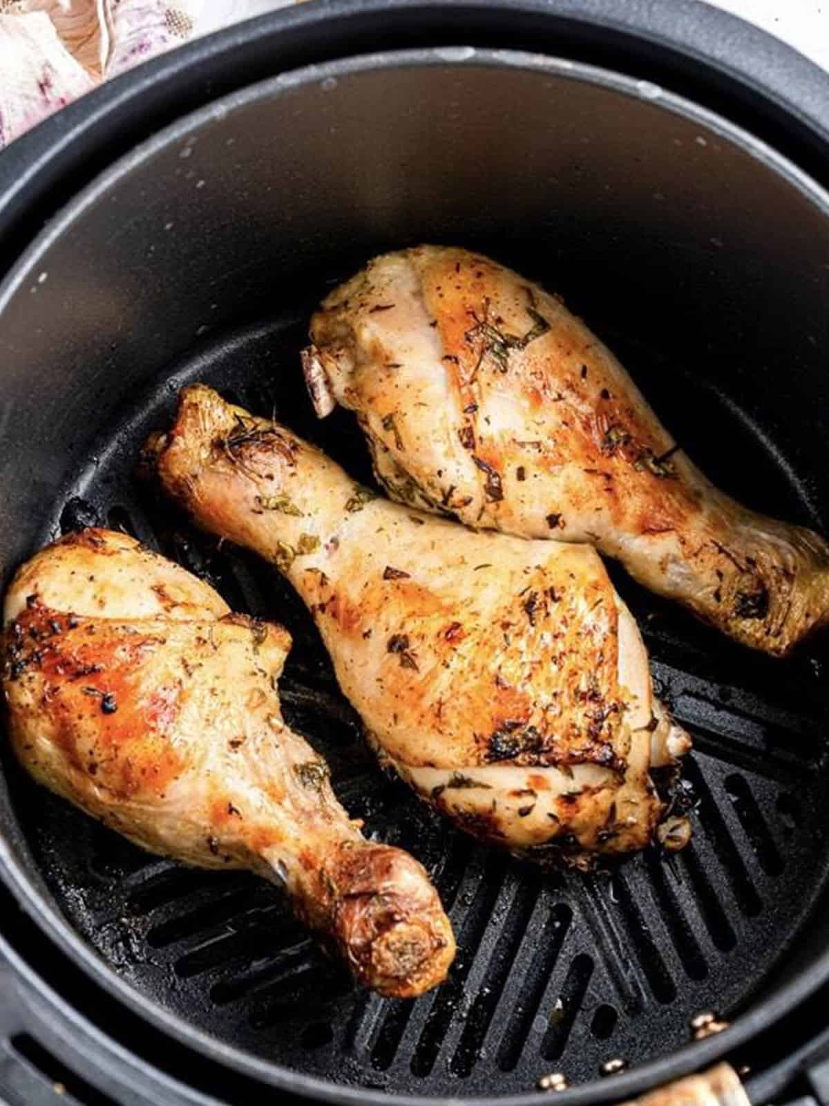 Golden cooked chicken drumsticks in the air fryer basket.