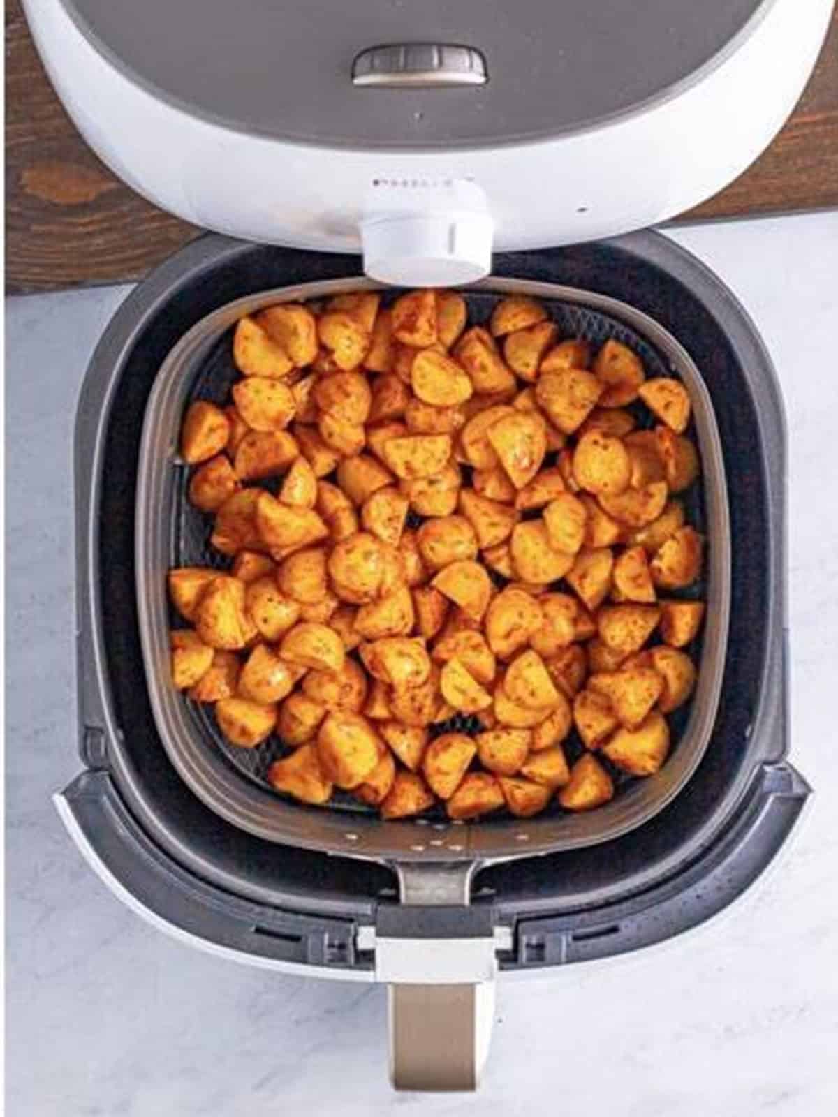 Seasoned potatoes in a single layer in the air fryer basket.