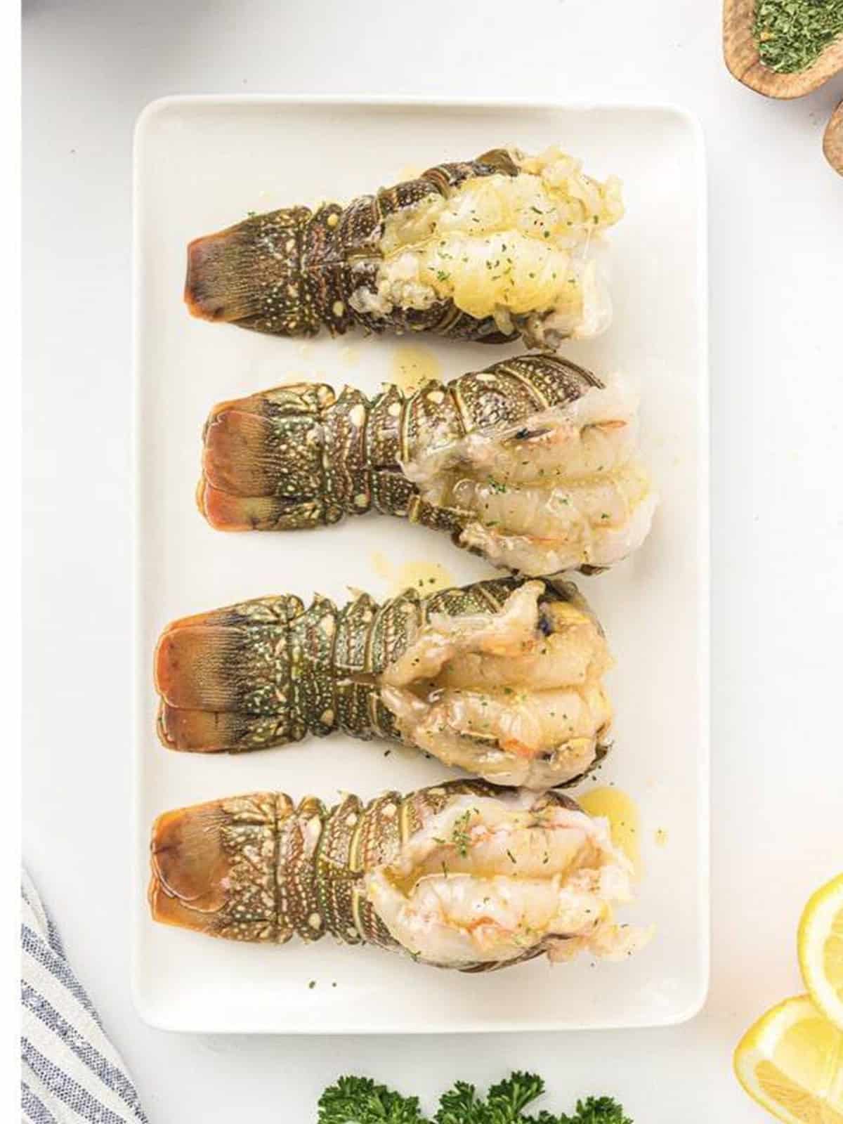 Lobster tails brushed with seasoned butter on a plate.