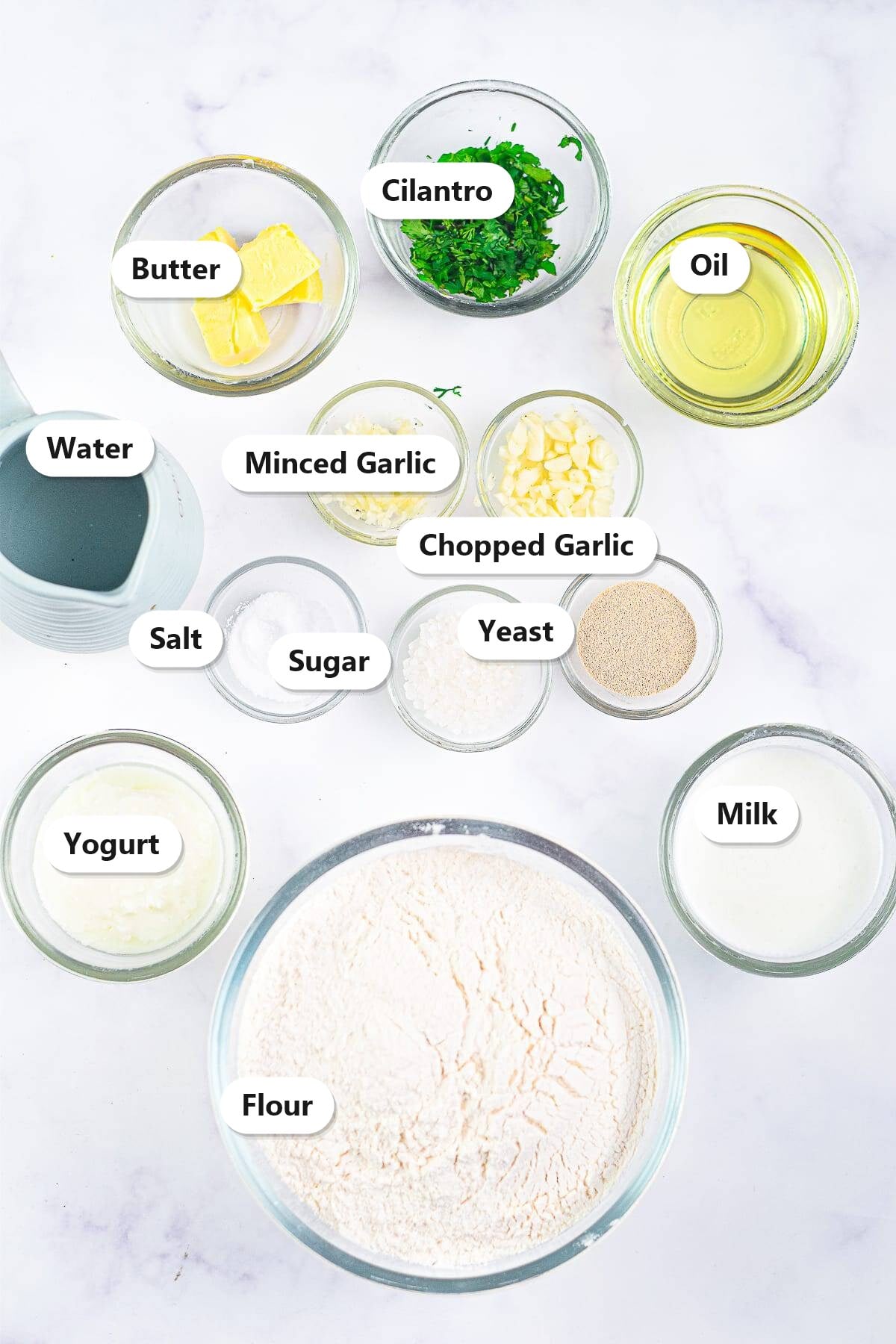 Labeled ingredients for air fryer naan bread including flour, yeast, yogurt, milk, garlic, and butter.