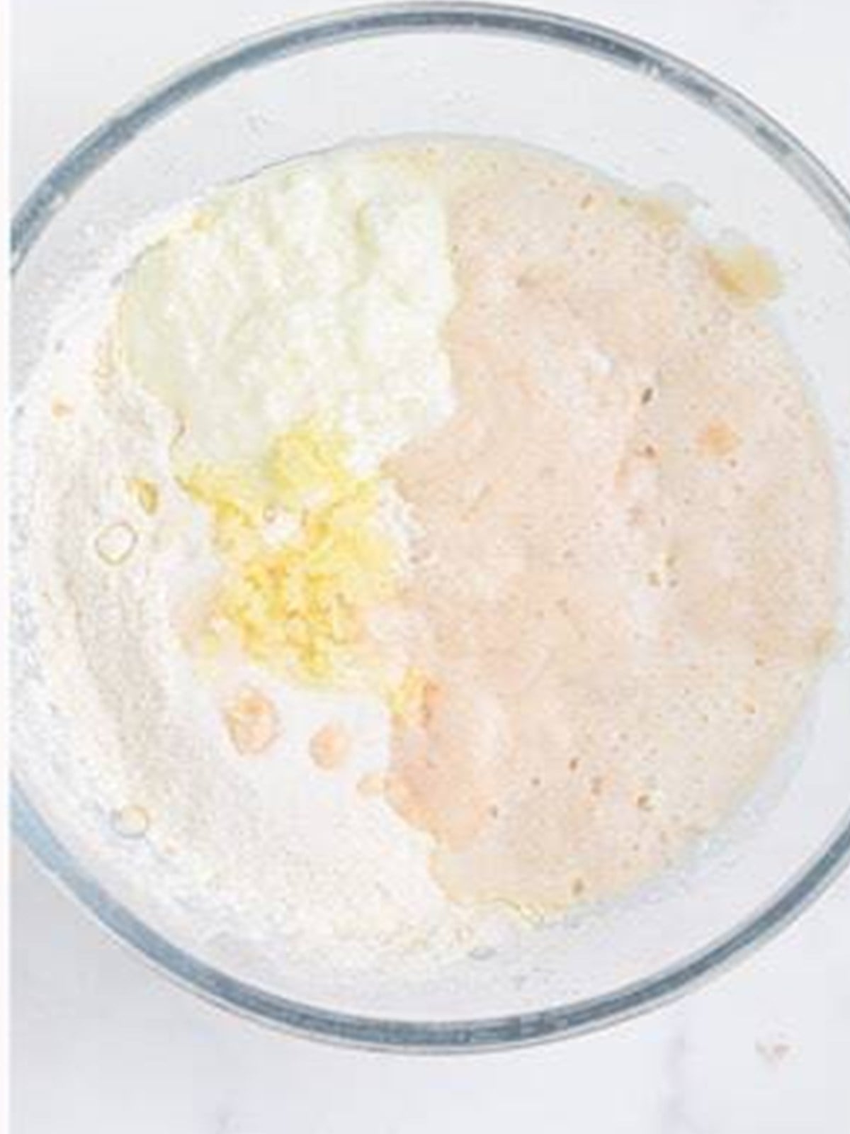 Flour, yogurt, oil, and yeast combined in a bowl to make naan dough.