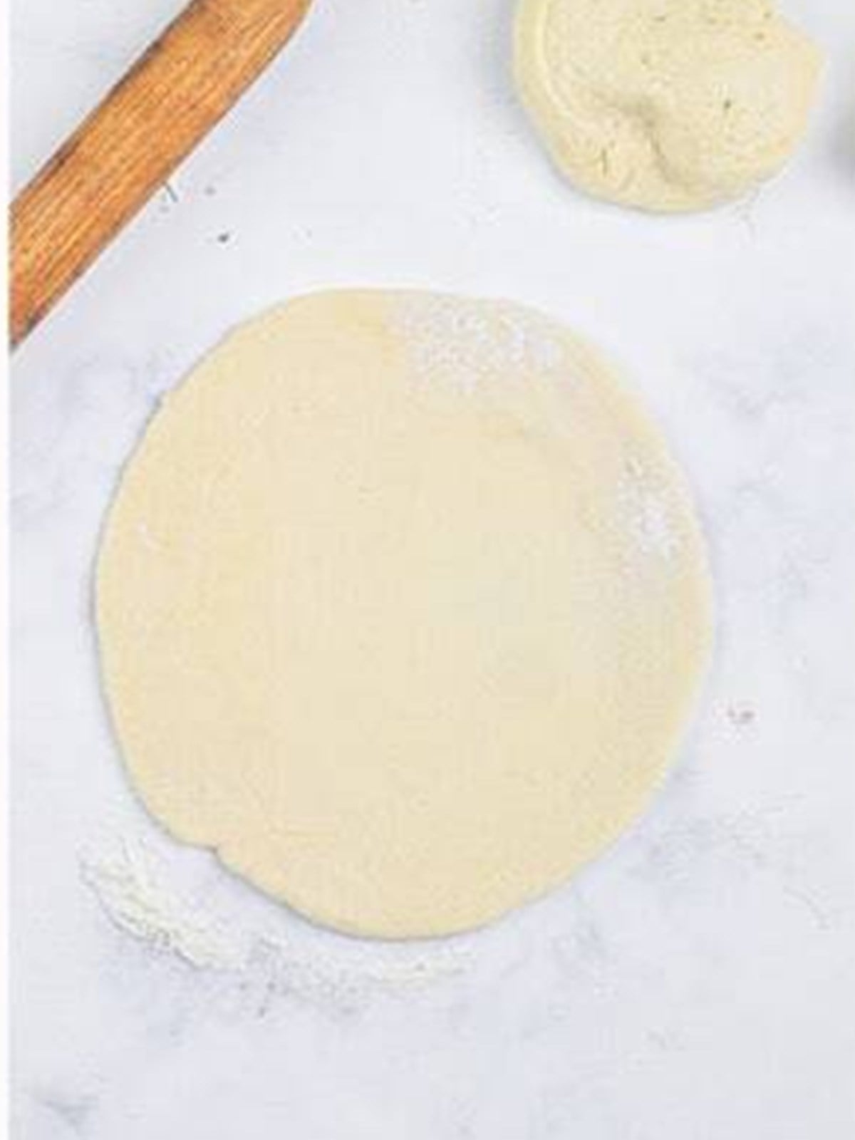 Naan dough rolled flat into a round with a rolling pin.