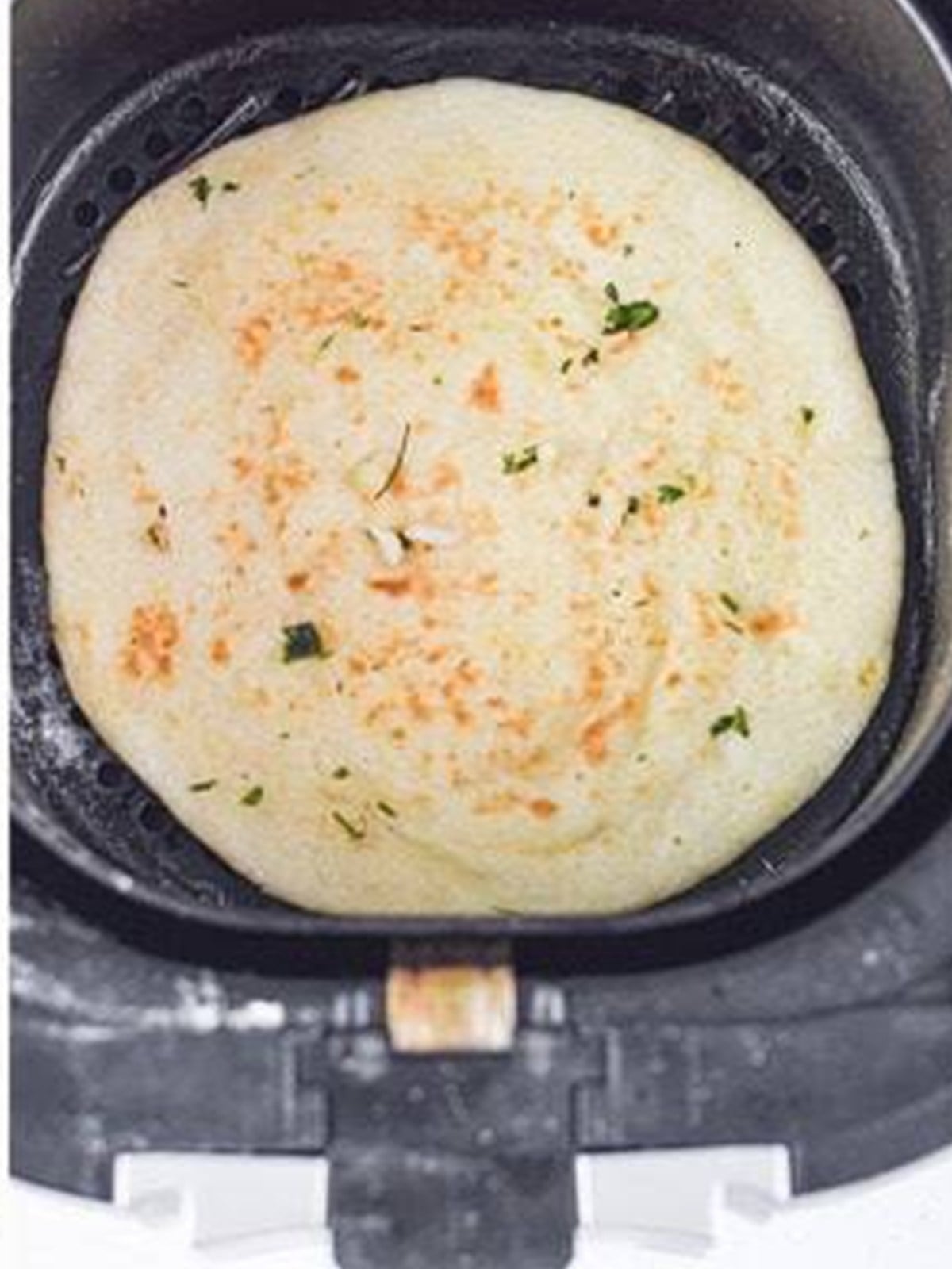 Golden cooked air fryer naan bread in the basket.