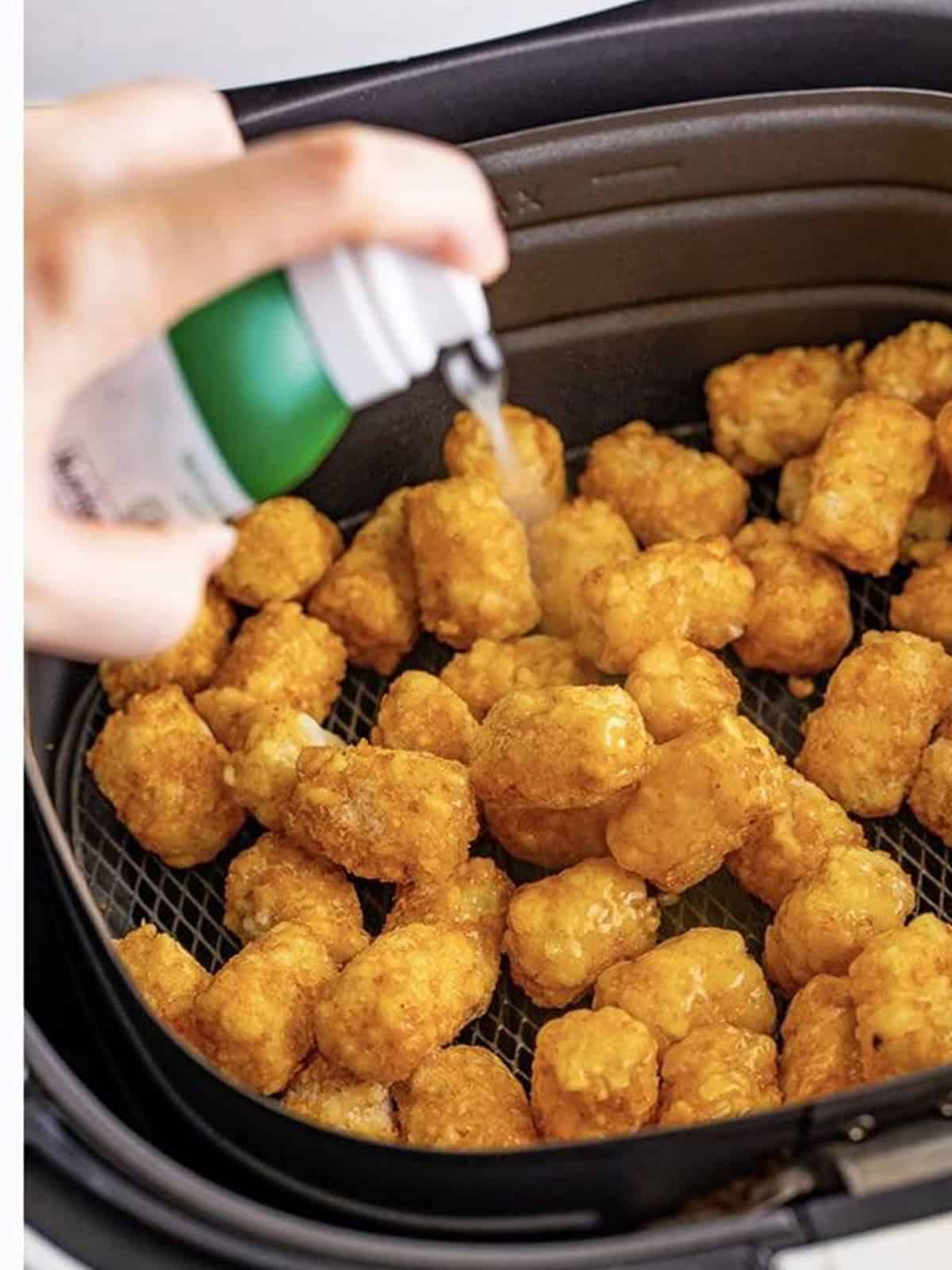 Tater tots in the air fryer basket sprayed lightly with olive oil.