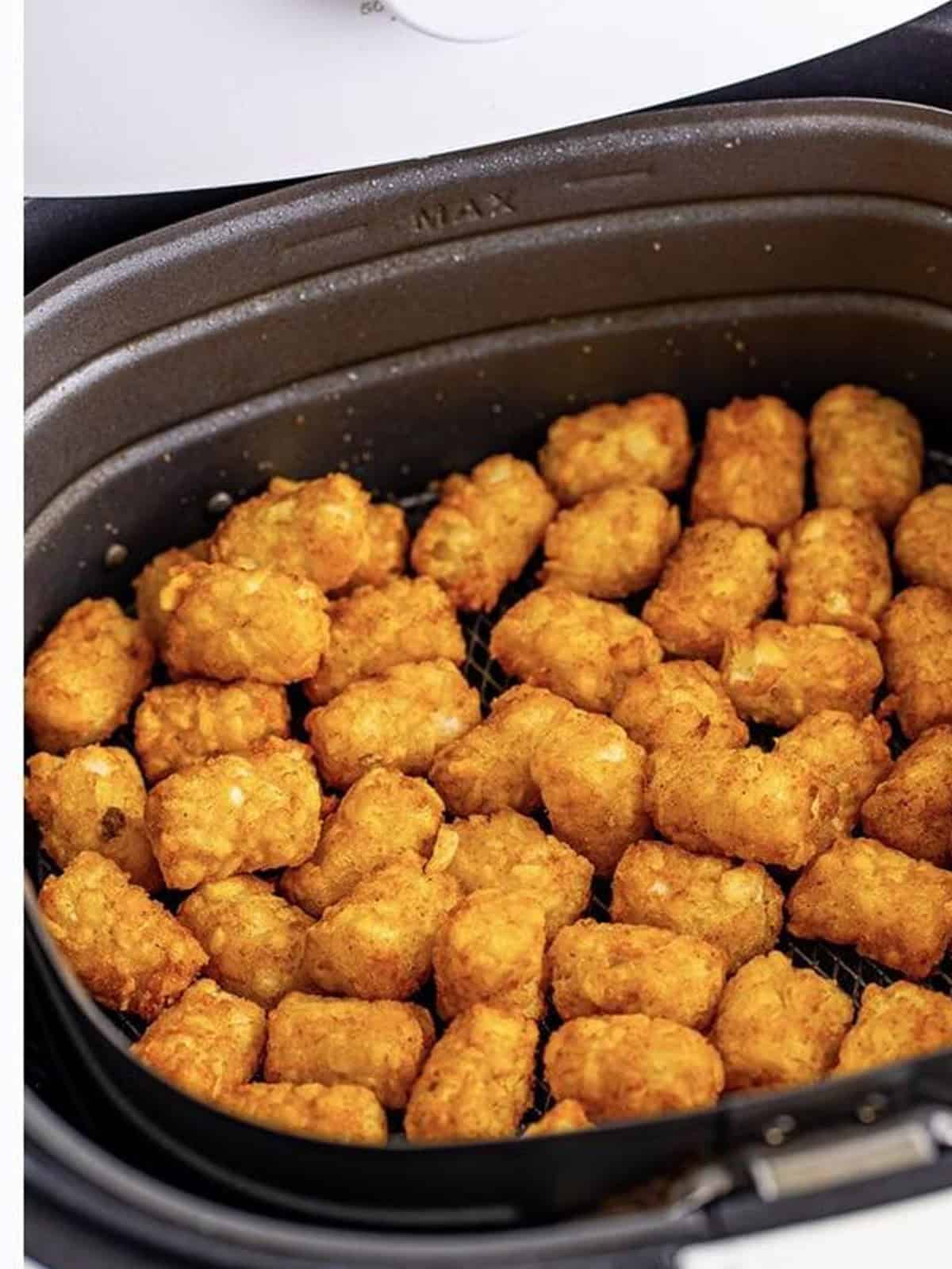 Golden, crispy air fryer tater tots in the basket.