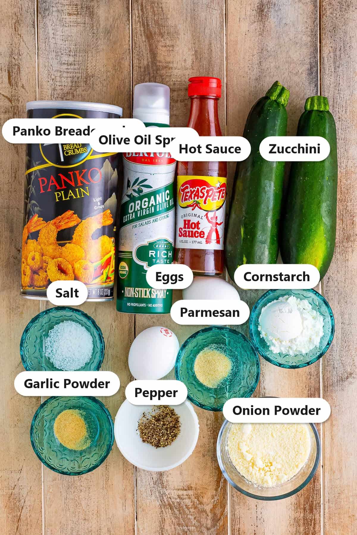 Labeled ingredients for air fryer zucchini fries including zucchini, panko breadcrumbs, parmesan, eggs, cornstarch, hot sauce, and seasonings.