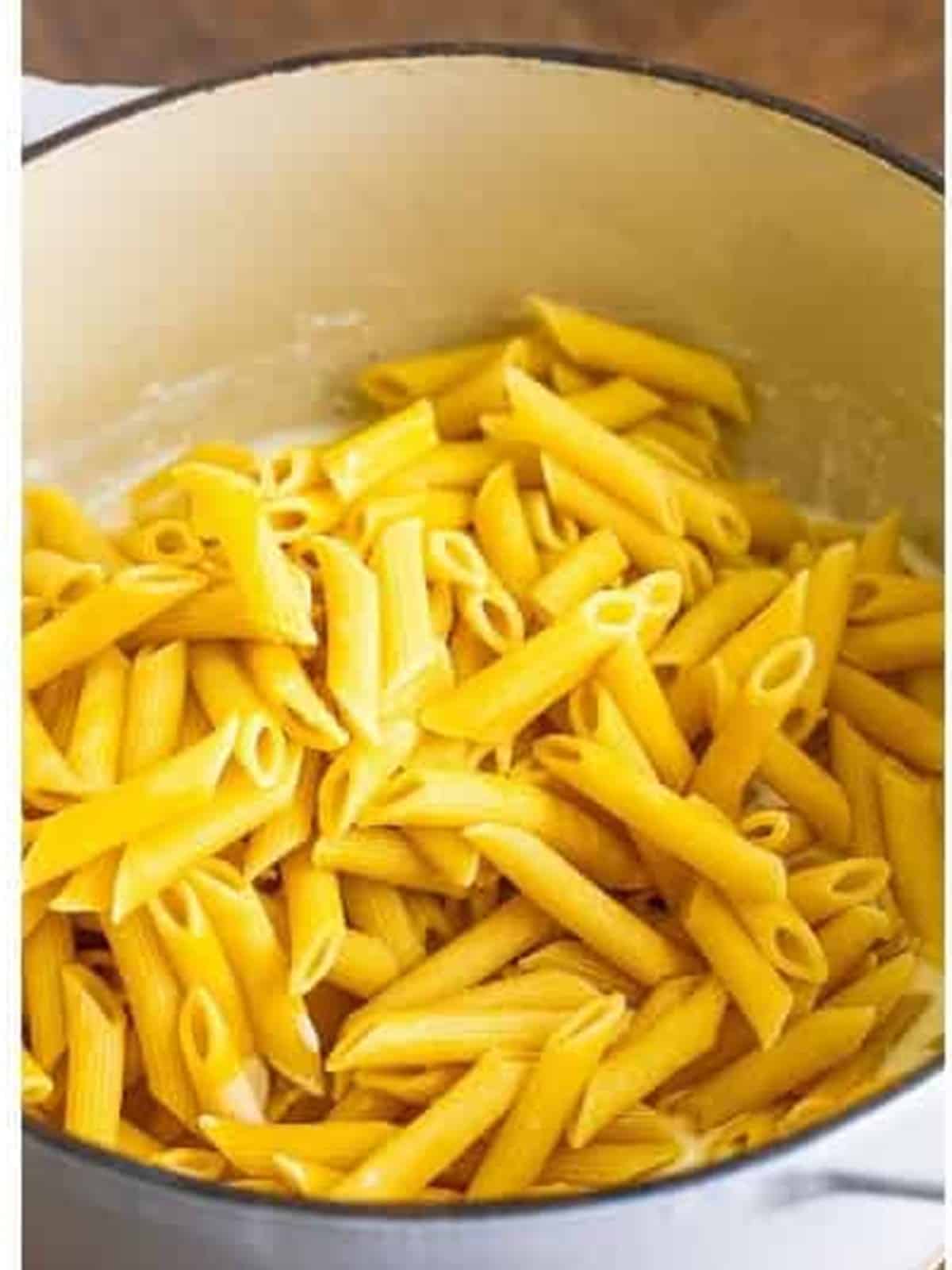 Cooked penne pasta added to the creamy alfredo sauce.