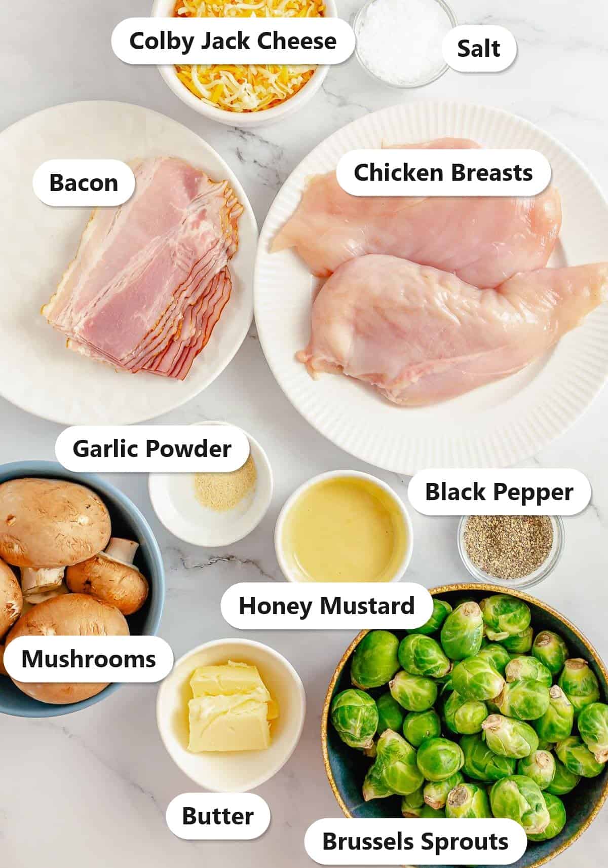 Labeled ingredients to make Alice Springs chicken including chicken breasts, bacon, mushrooms, Brussels sprouts, honey mustard, colby jack cheese, butter, and seasonings.